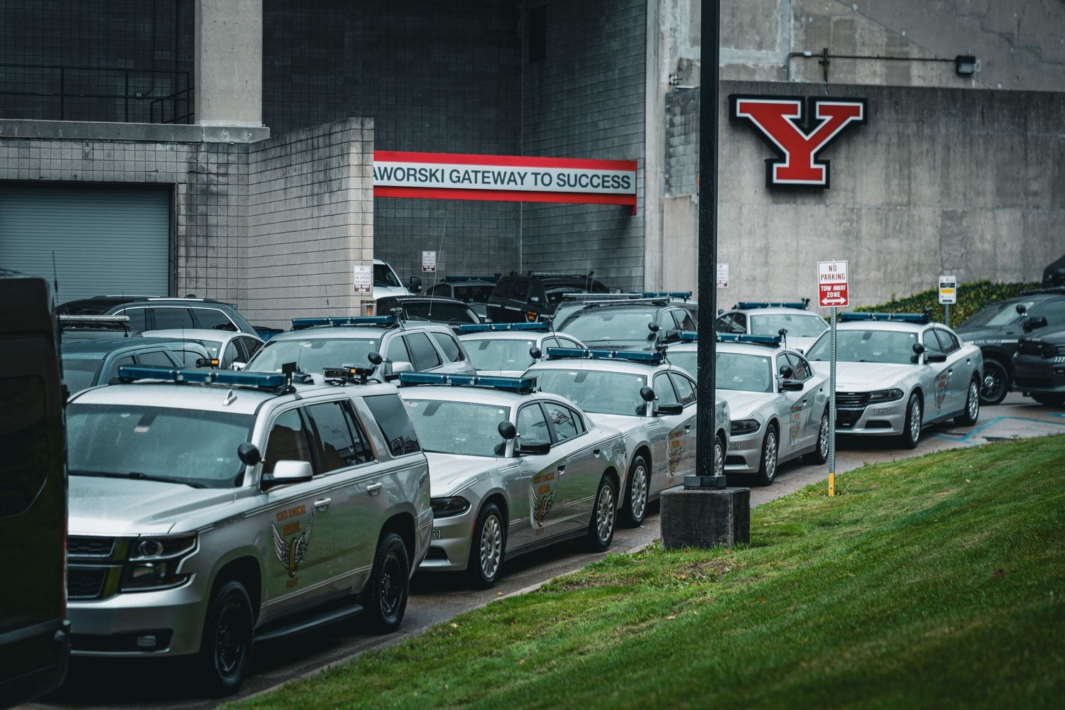 Cars line up in a parking lot with a Youngstown State University logo visible on the building.