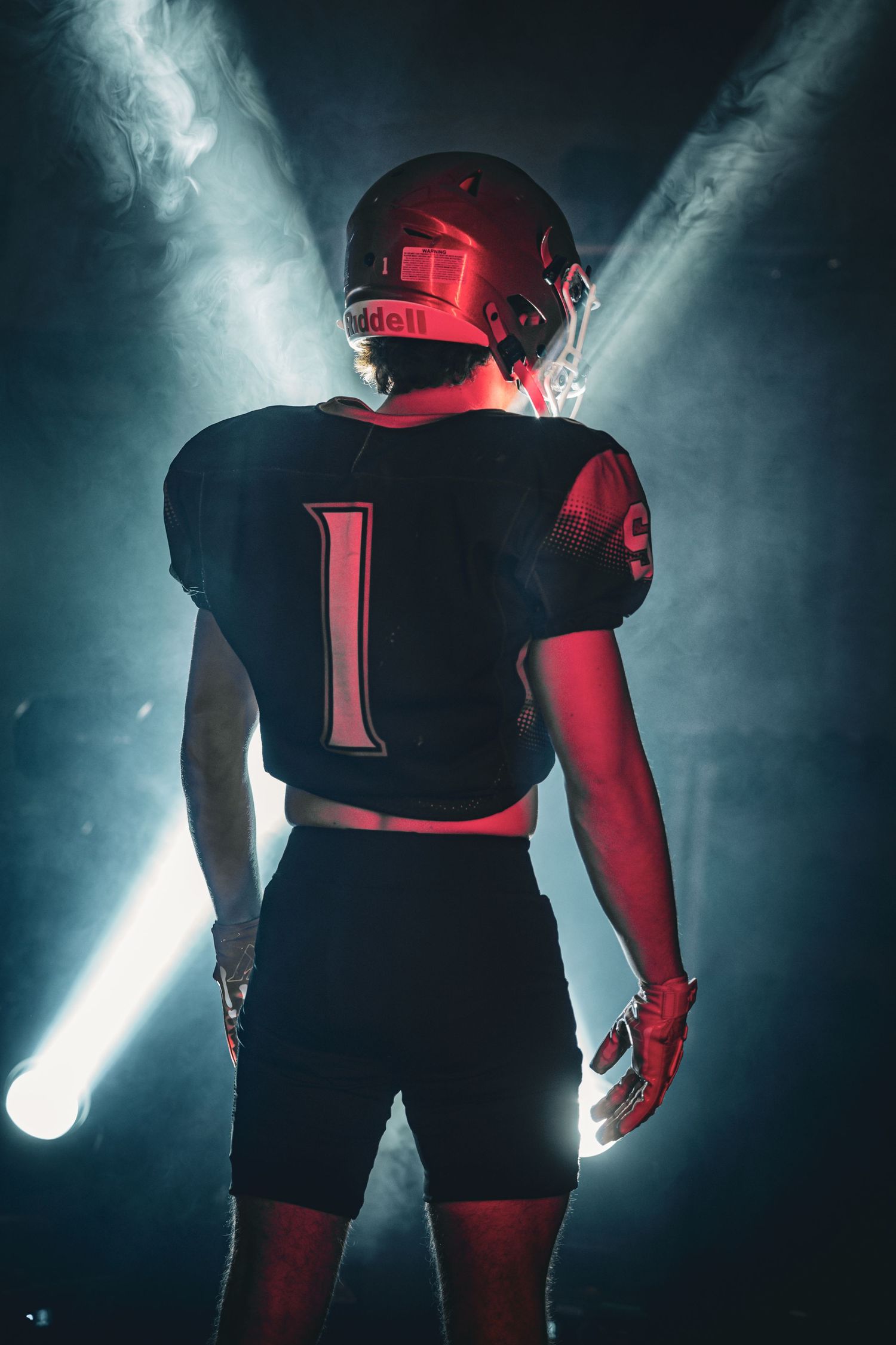 Dramatic silhouette shots of football players in black uniforms with moody lighting and smoke effects.