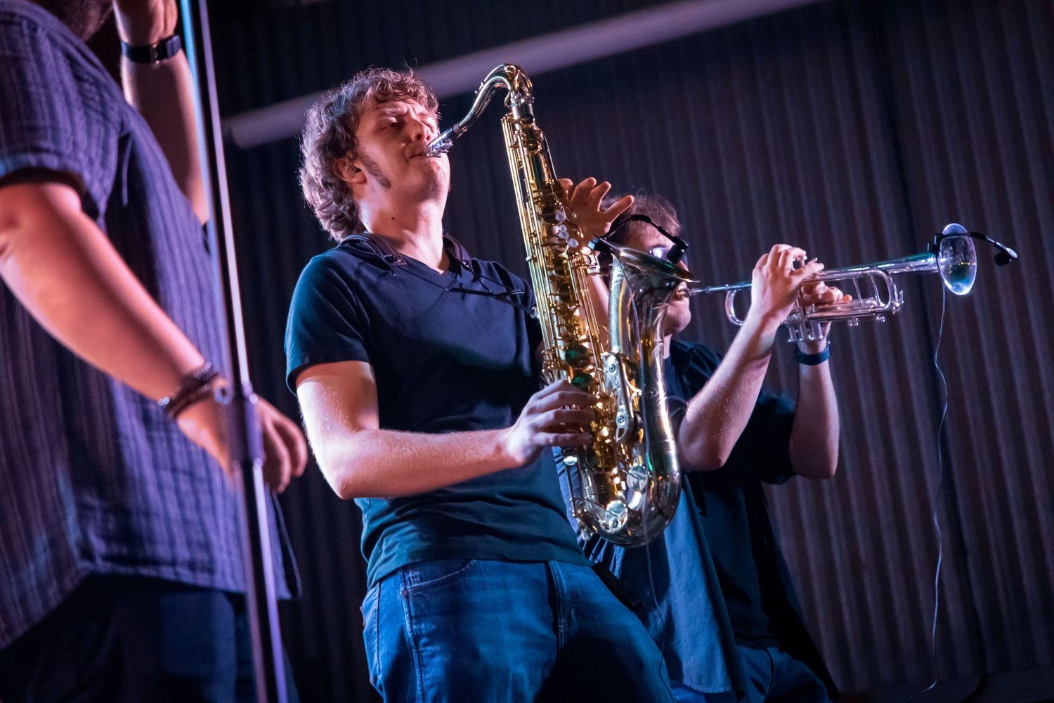 Musicians playing saxophone and brass instruments during live performance.