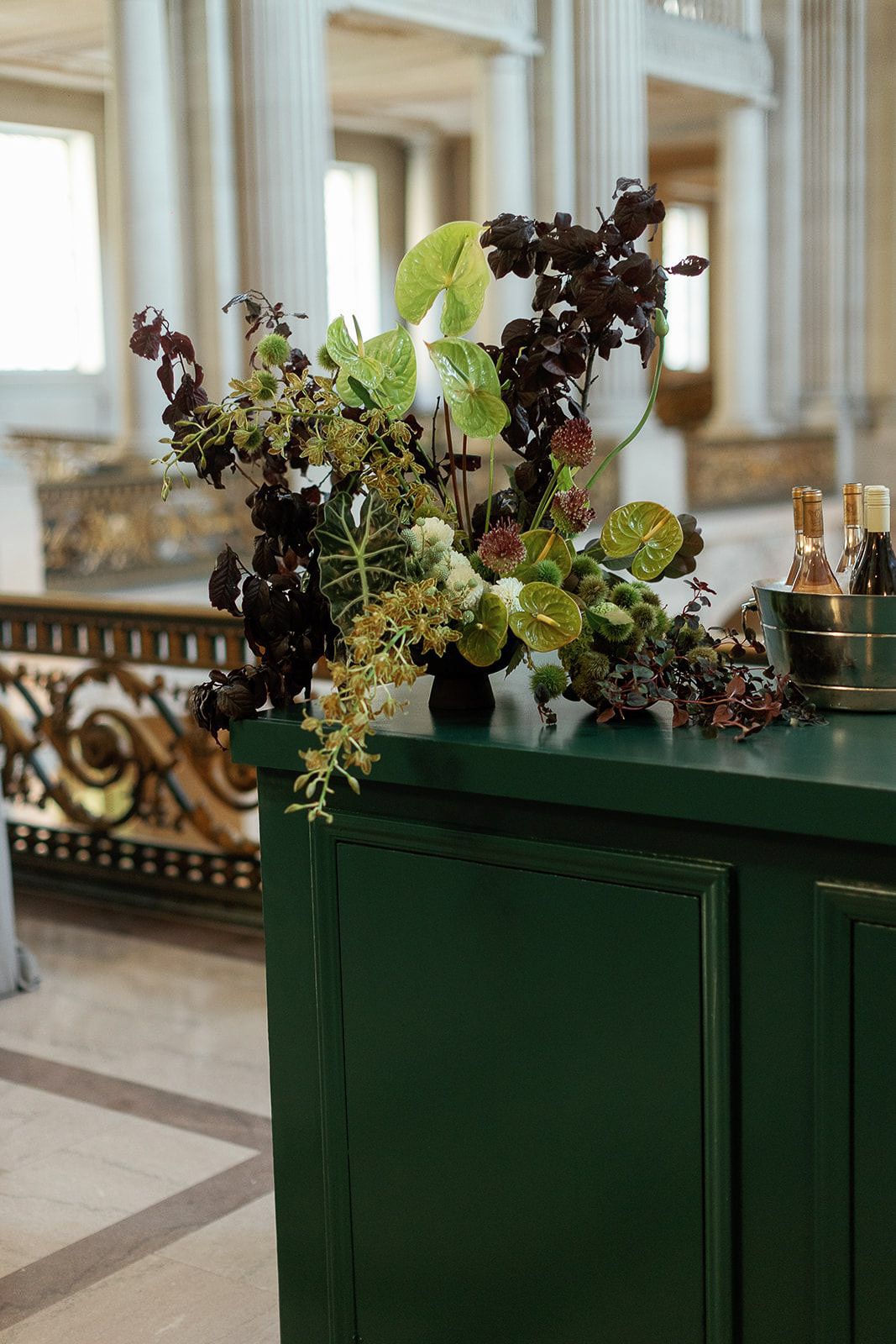 Decorative green planters with succulent arrangements line an elegant columned hallway.
