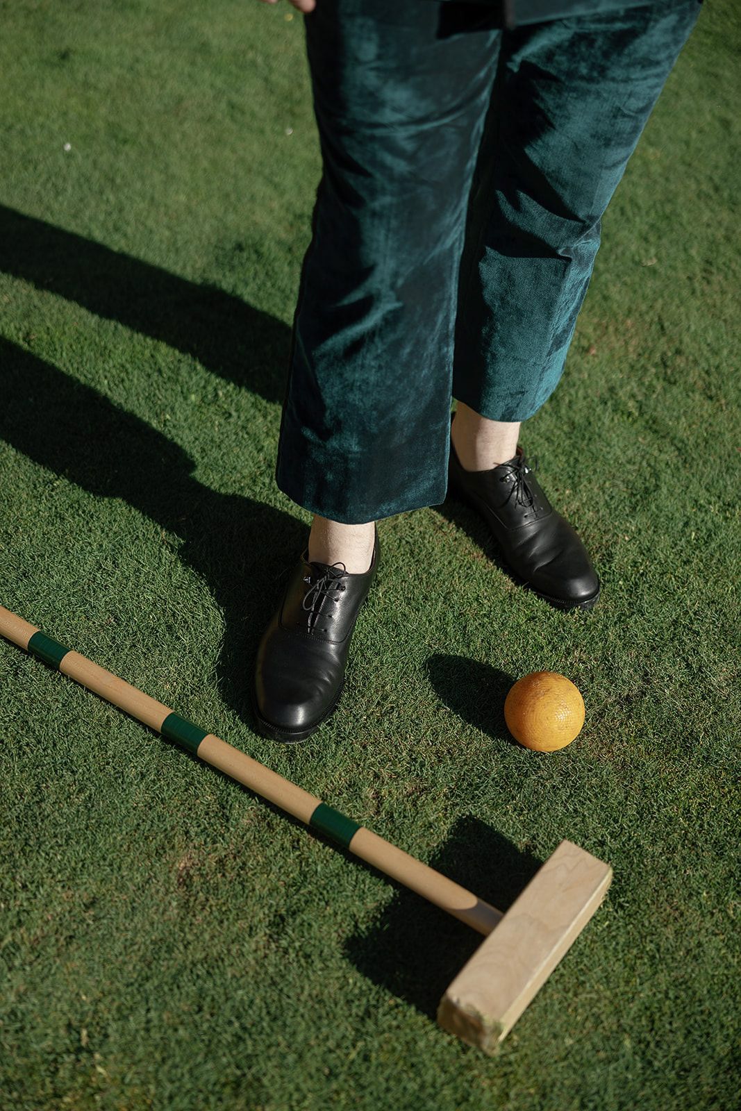 Croquet equipment on green lawn with wooden mallet and ball.