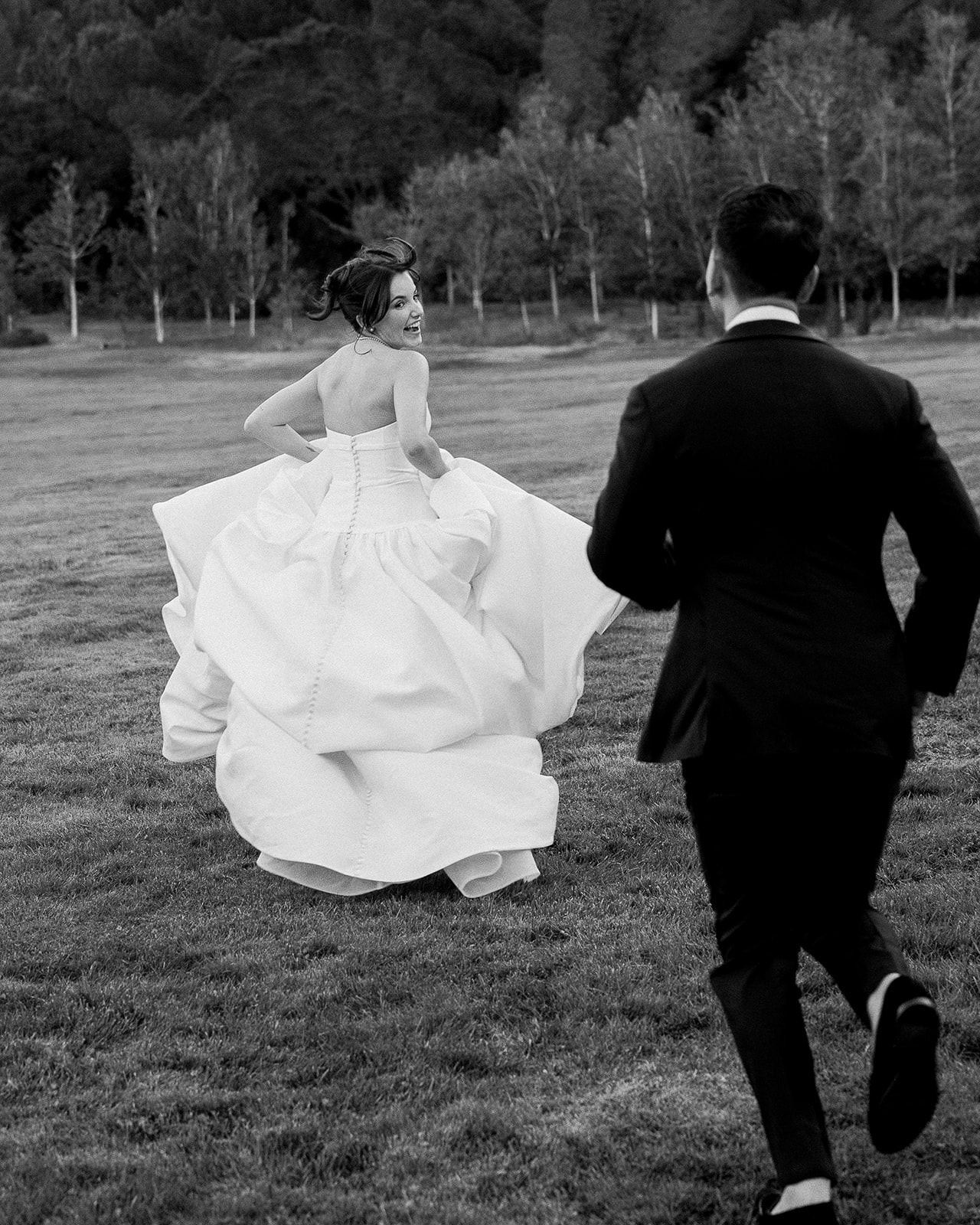 Wedding portrait photography of a groom chasing the bride on the lawn at Stonepine Estate in Carmel Valley, California.