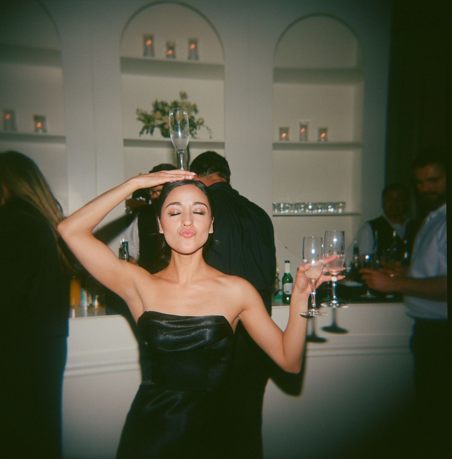 Dark party scene with guests dancing in celebratory poses.
