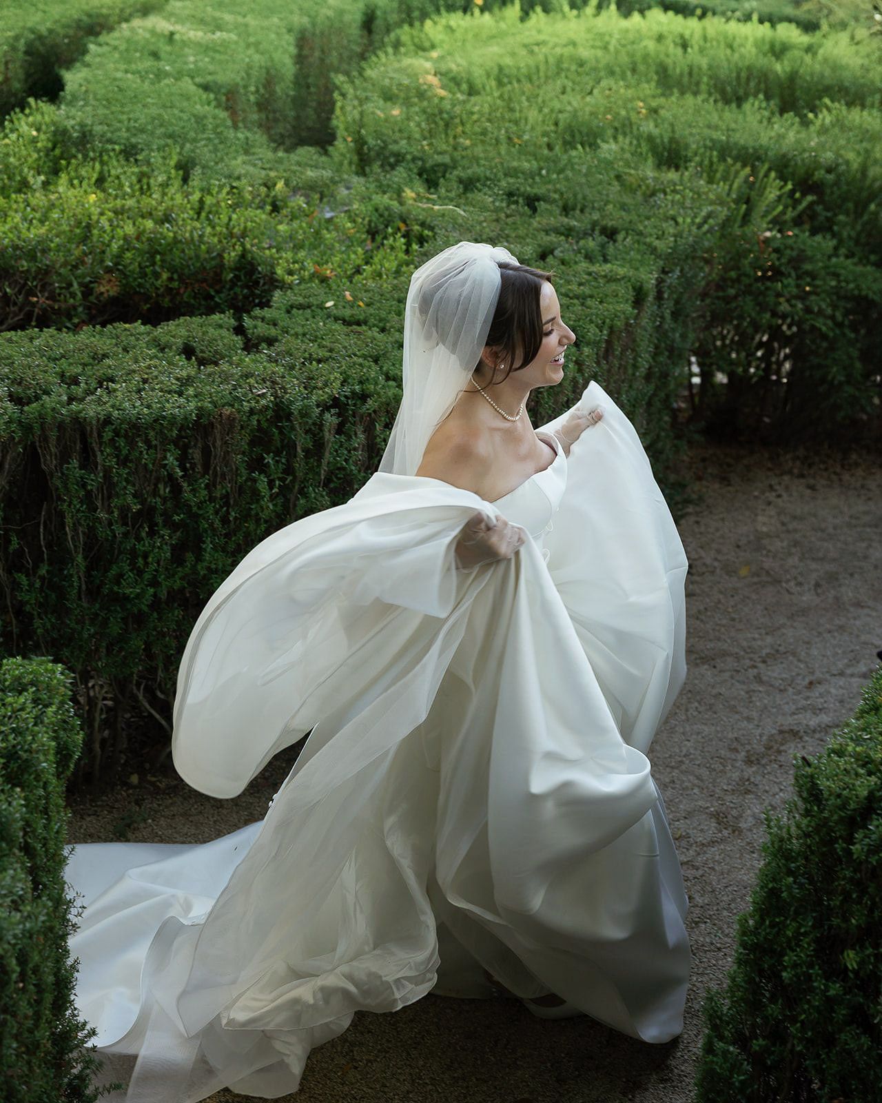 Wedding portrait photography of a bride running through the hedge maze at Stonepine Estate in Carmel Valley, California.