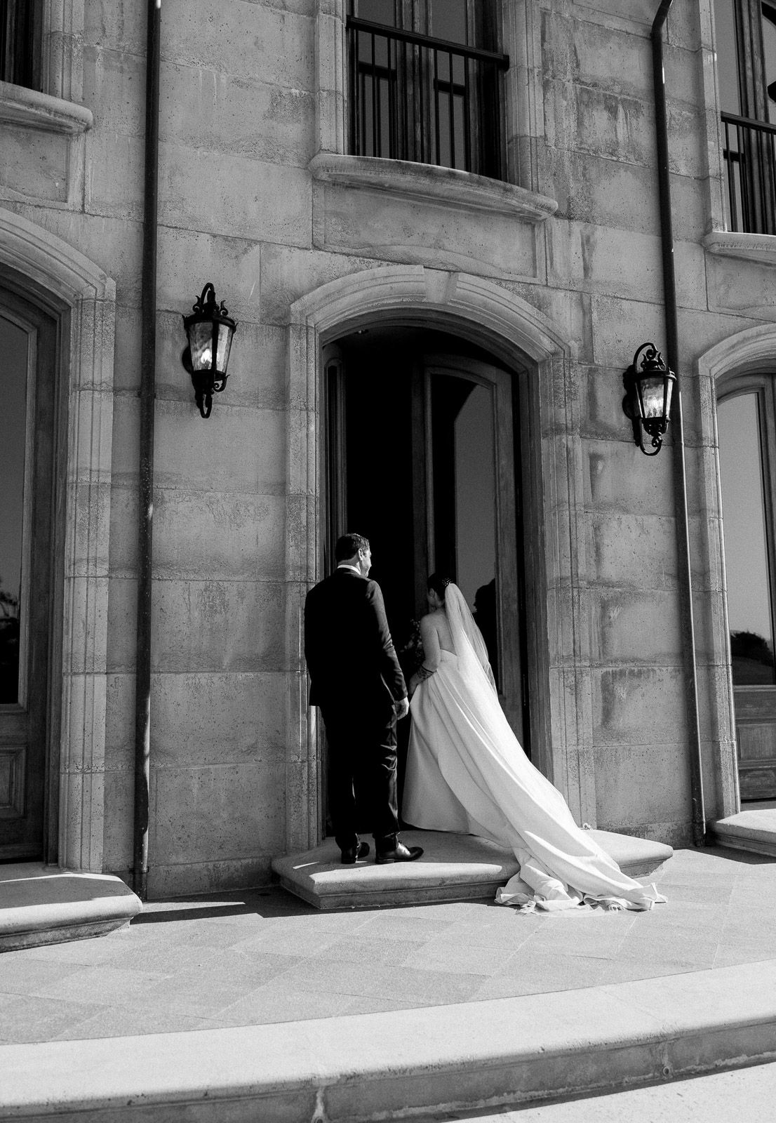 Black and white sequence of a wedding dress flowing through stone archways.