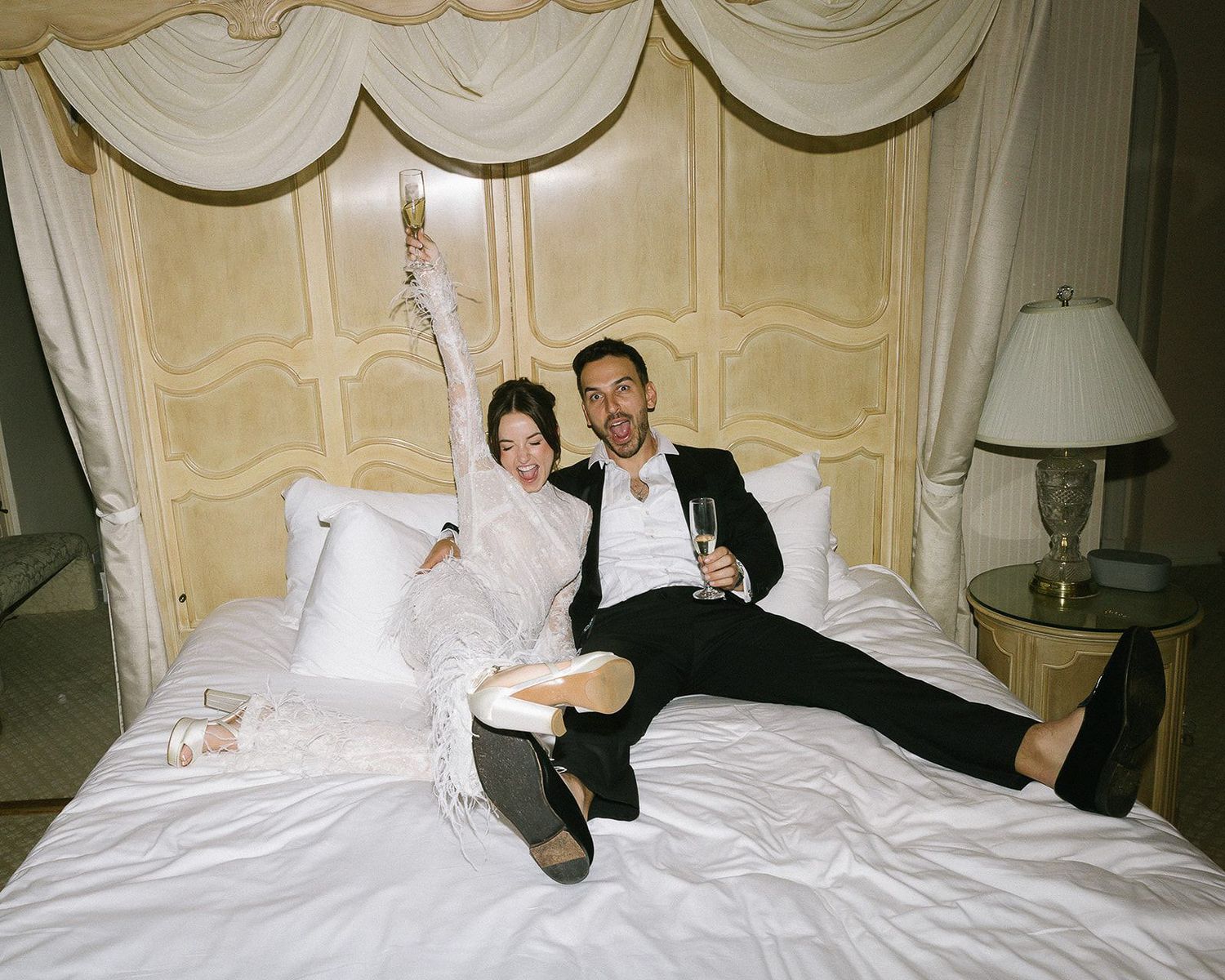After-party wedding photography of the couple sitting on a bed at Stonepine Estate in Carmel Valley, California.