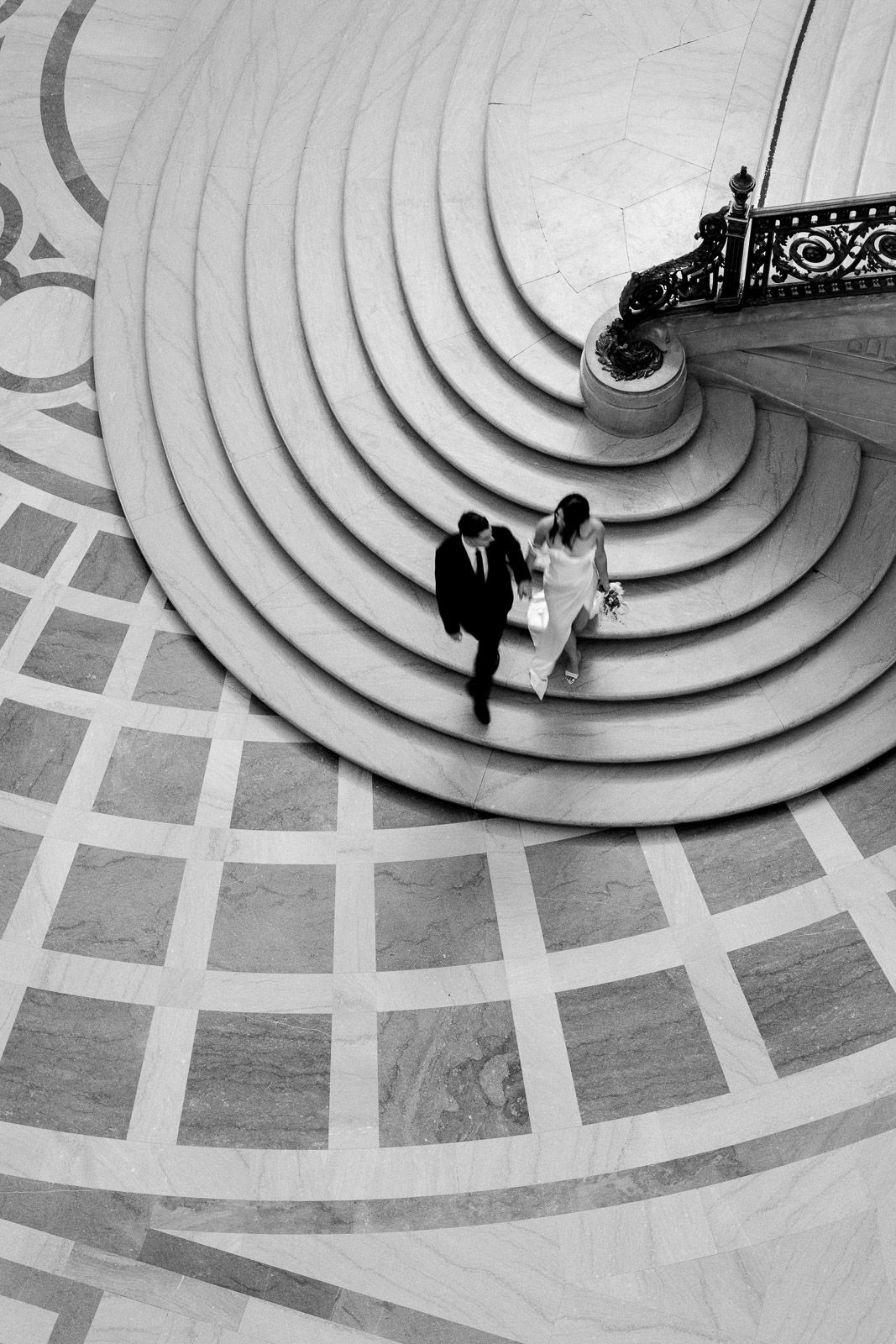 Elopement photography of a couple walking down the grand staircase at San Francisco City Hall.