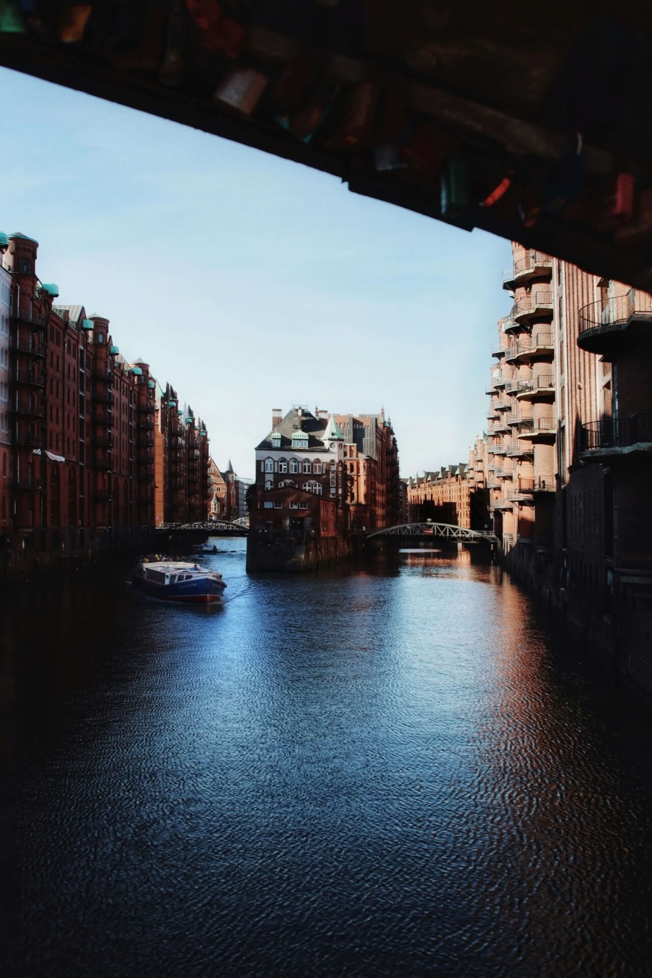 Architektonische Ansicht historischer Gebäude entlang des Kanals in der Hamburger Speicherstadt, mit einem kleinen Schiff in der Mitte.
