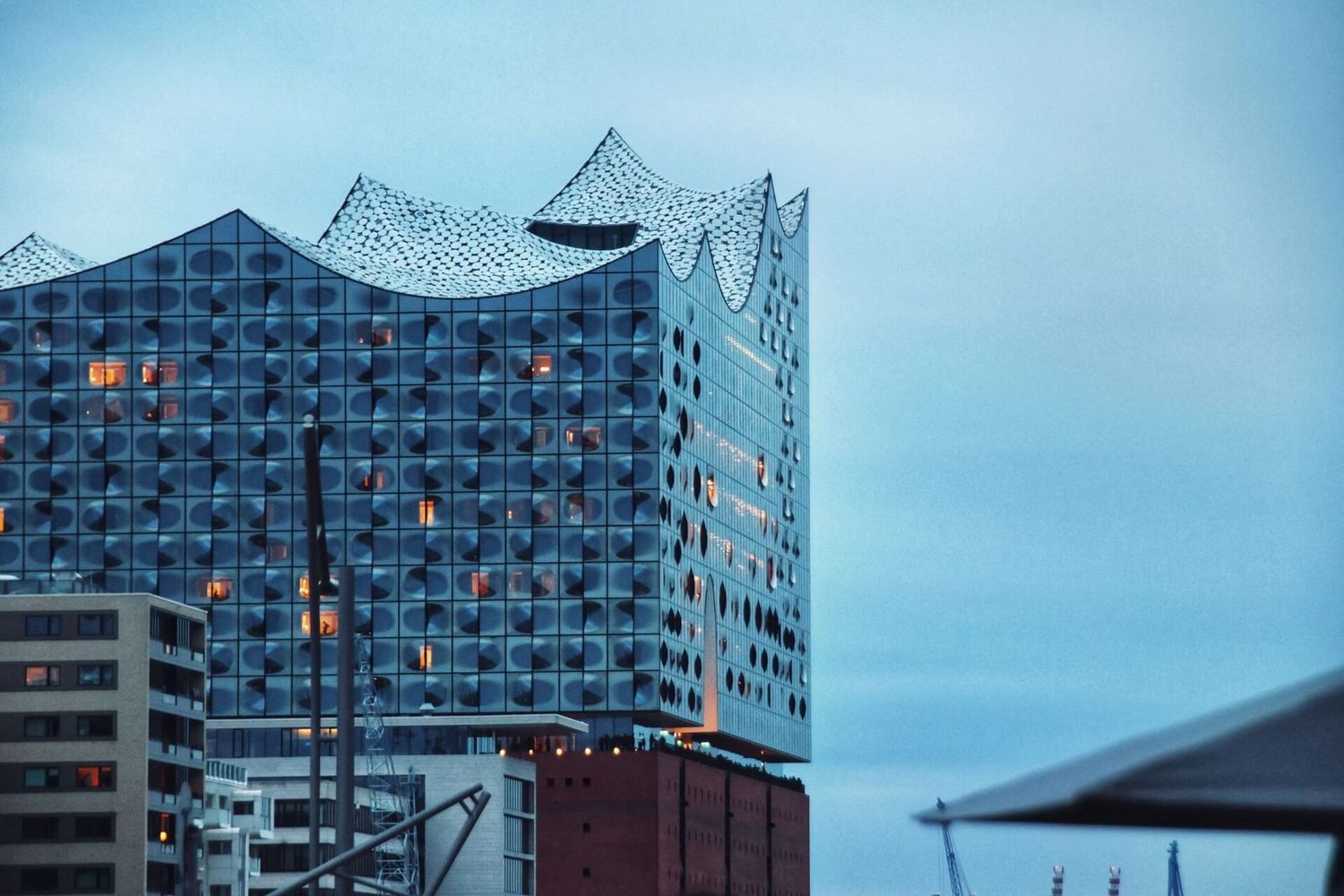 Die bekannte Elbphilharmonie in Hamburg erstrahlt in der Abenddämmerung in blauem Licht.