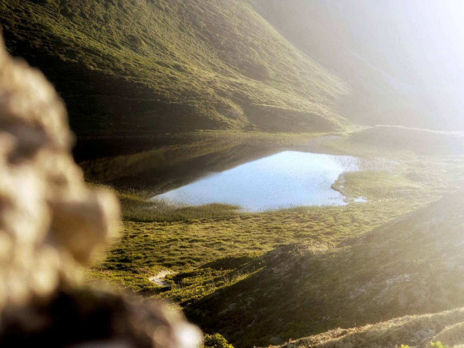 Dunstige Berglandschaft mit kleinem See, der durch eine felsige Öffnung sichtbar ist.