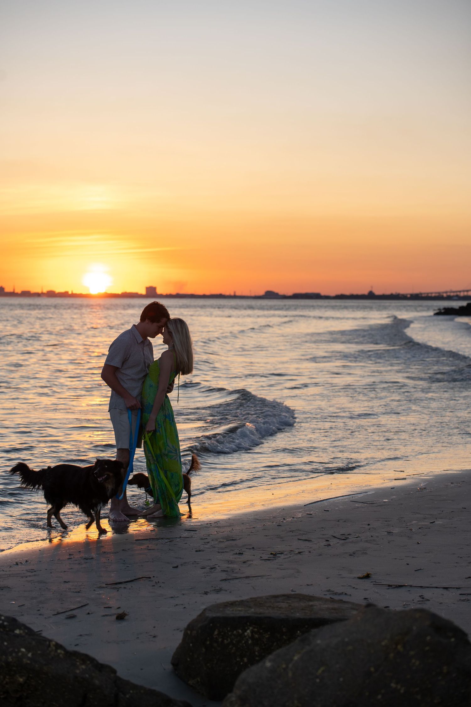 Couple sharing intimate moment on beach at sunset with dog.