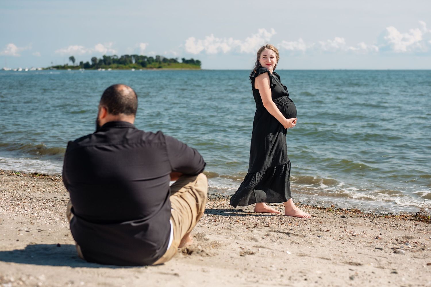 Couple relaxing on beach with scenic ocean view and distant shoreline.