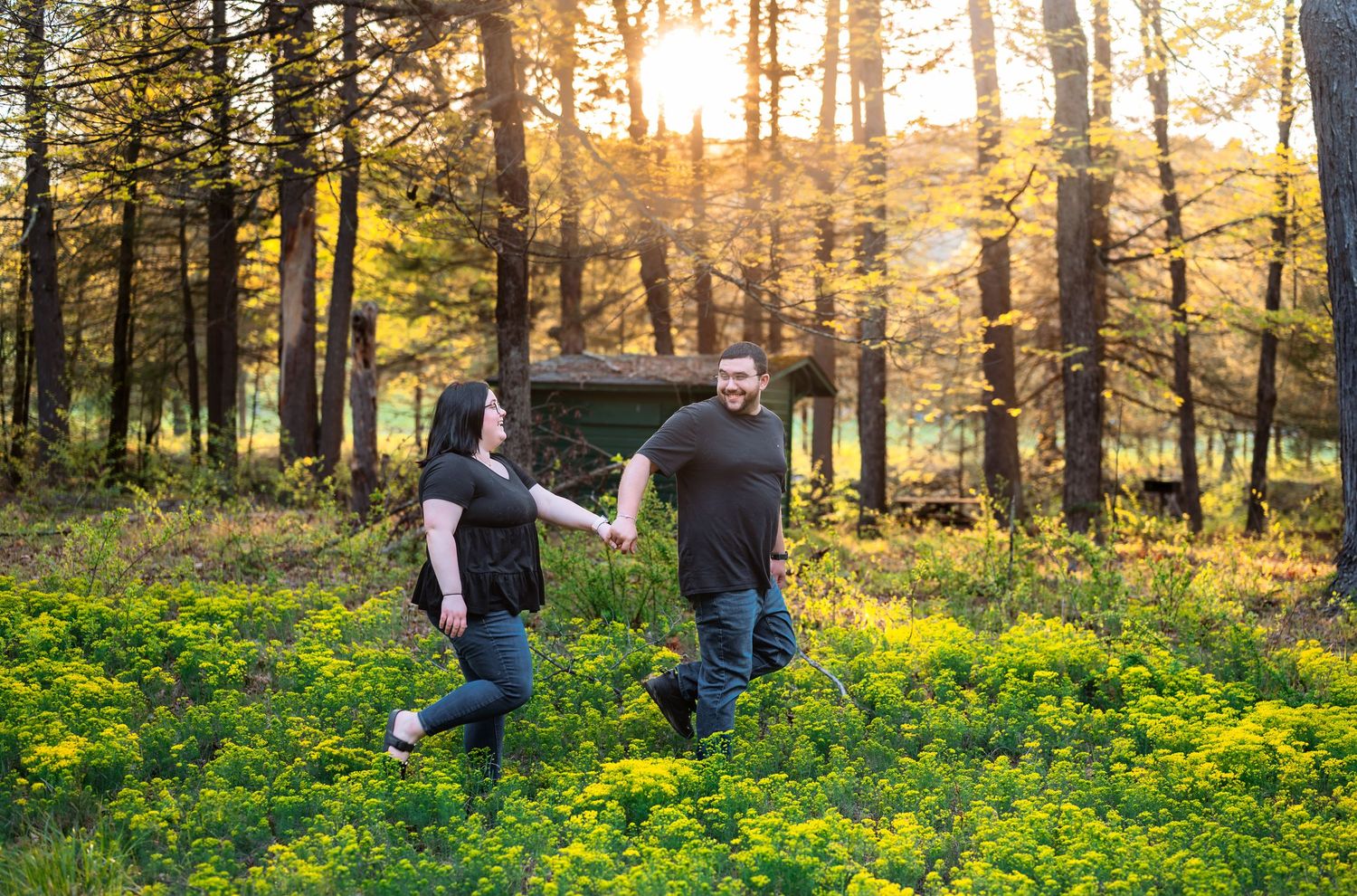 Silhouettes of people walking through a sunlit forest filled with yellow wildflowers.