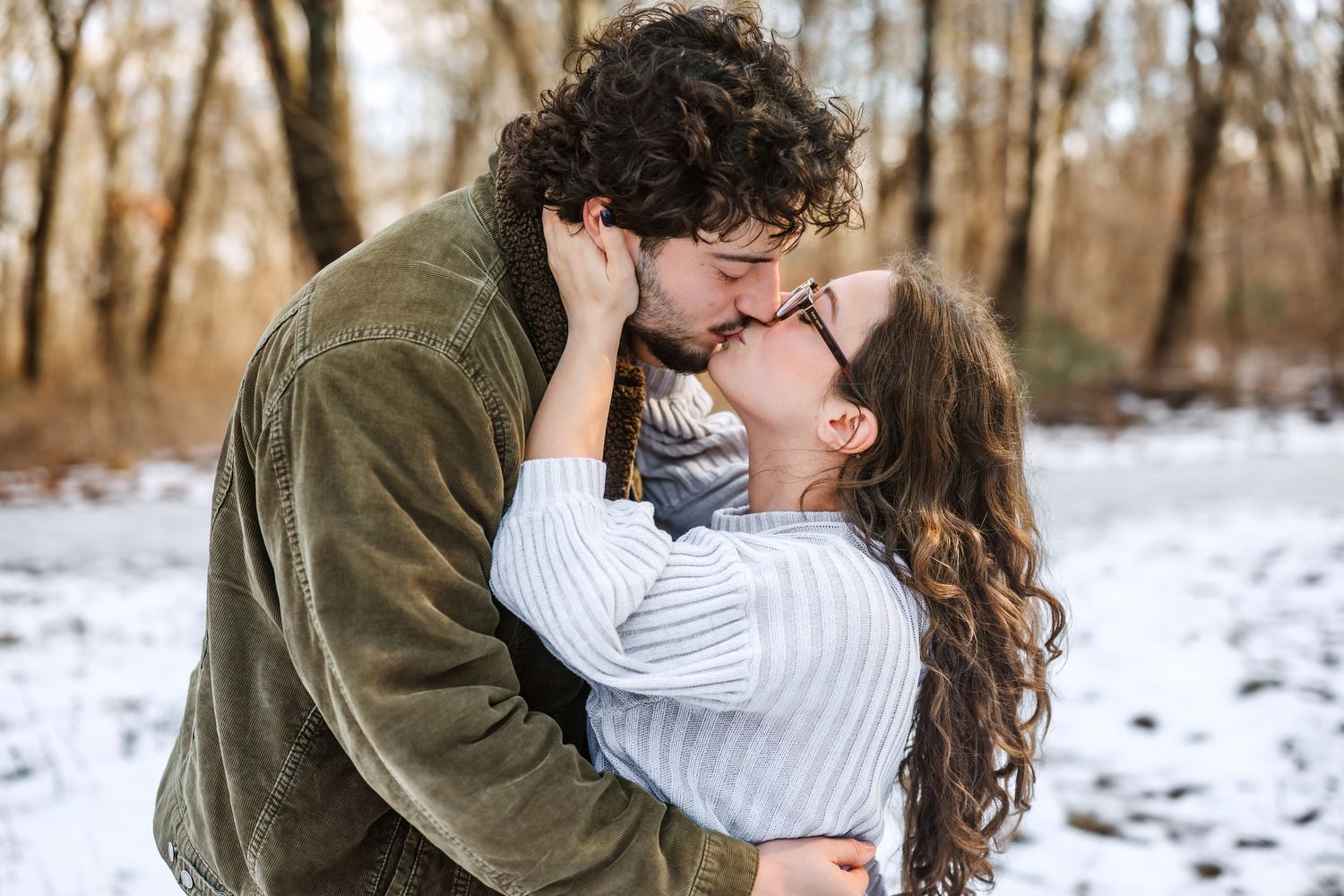 Winter engagement photoshoot in snowy woods showing romantic embrace.