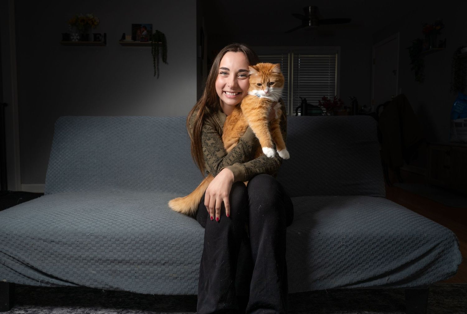 Lifestyle pet photography session featuring a ginger cat against dark backdrop.