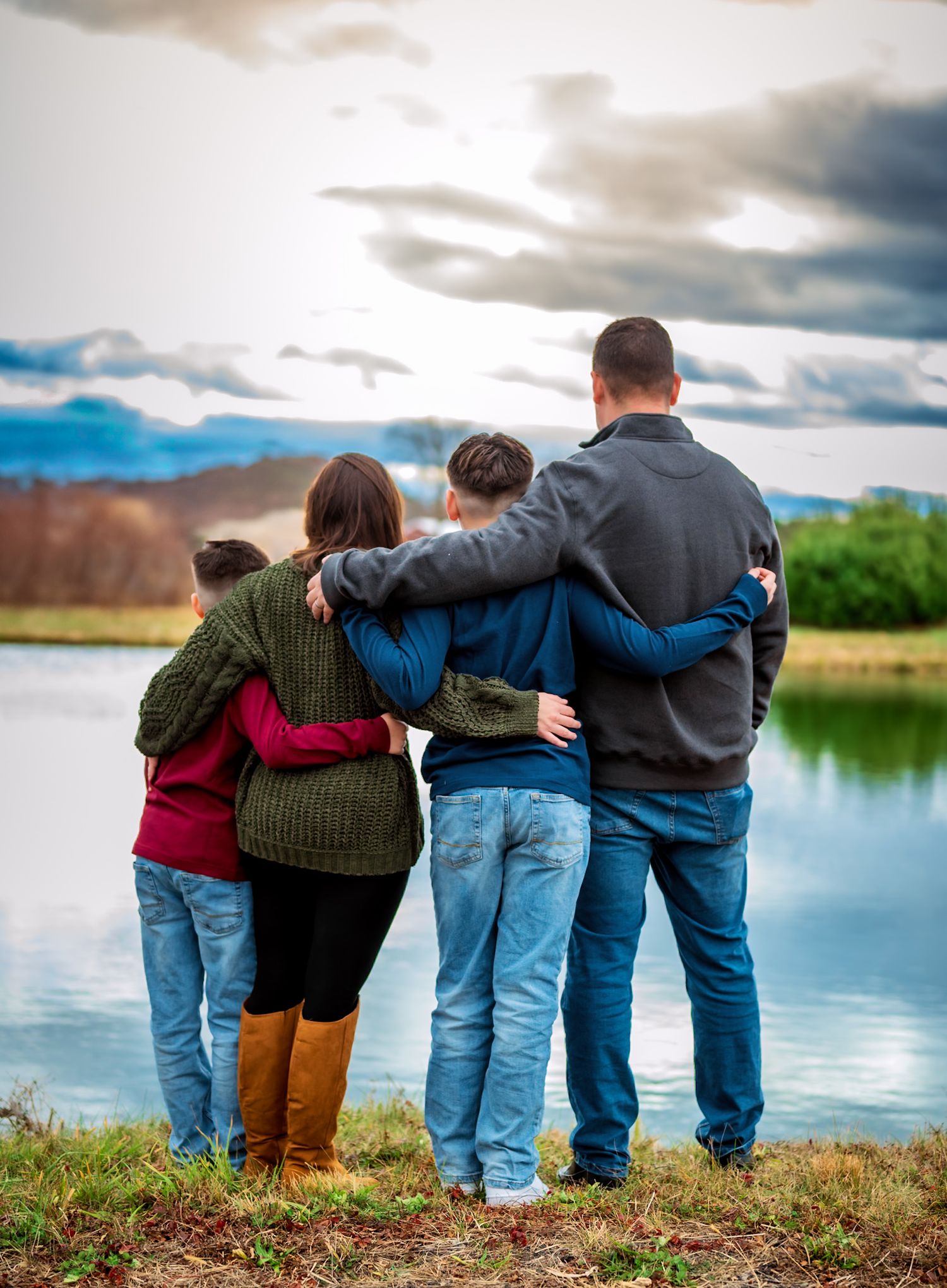 Group silhouette photo by a lake with dramatic cloudy sky in the background.