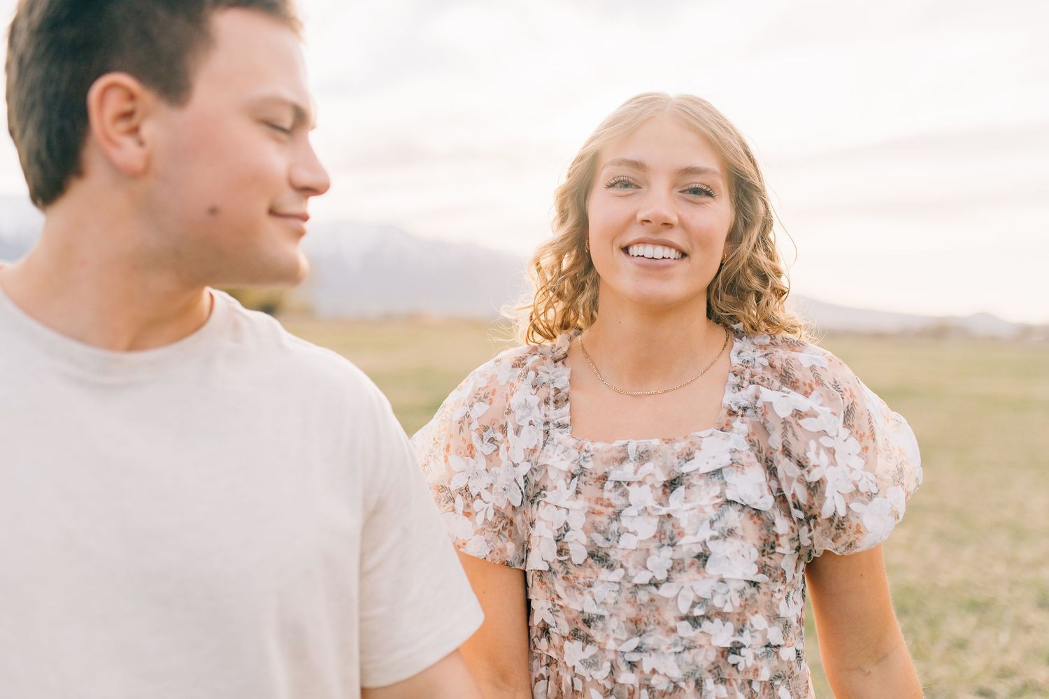 A couple walks together and shares a joyful moment in an outdoor setting during golden hour.