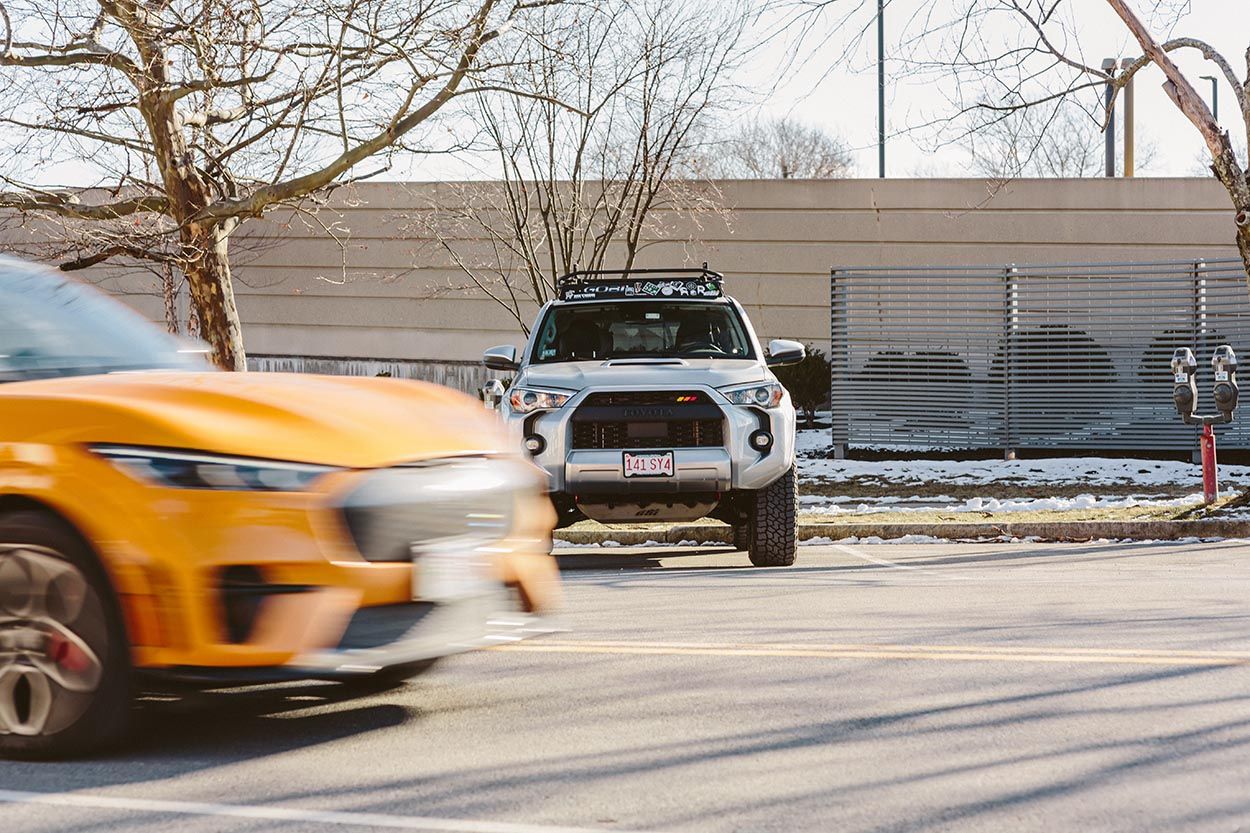 Urban vehicle photo of SUV parked by the side of the road with other car driving past