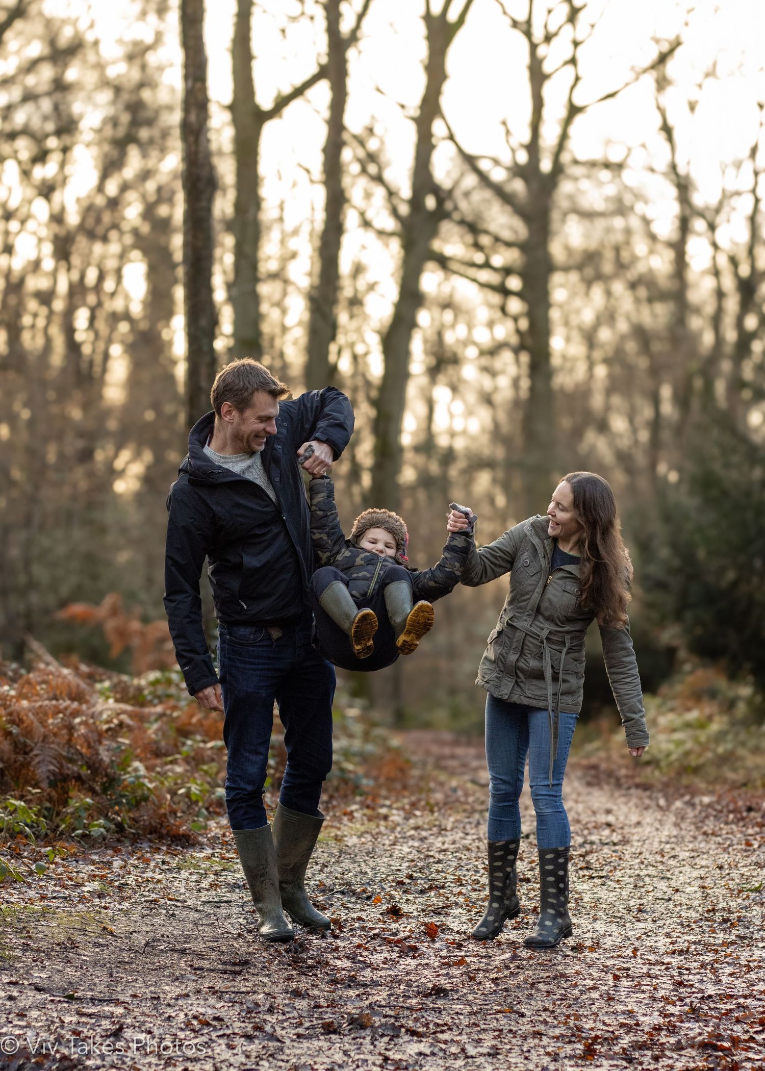 Playful sequence of family members bending down to pick up fallen leaves in an autumn forest setting.