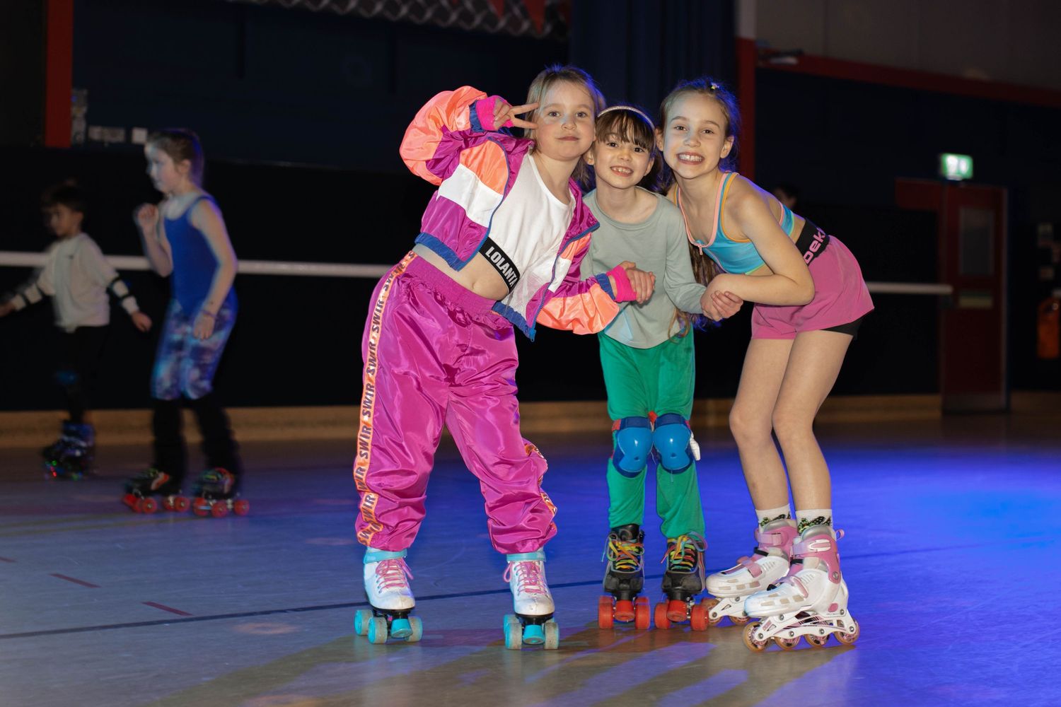 Colorful roller skating performance with dancers in bright costumes under blue stage lights.