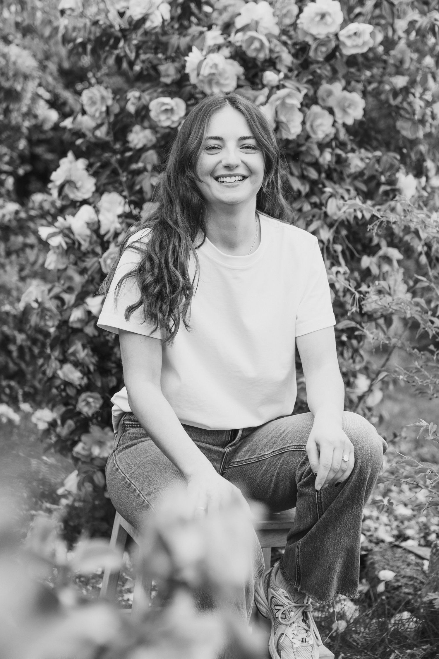 Black and white portrait series in a garden setting with flowers and natural lighting.