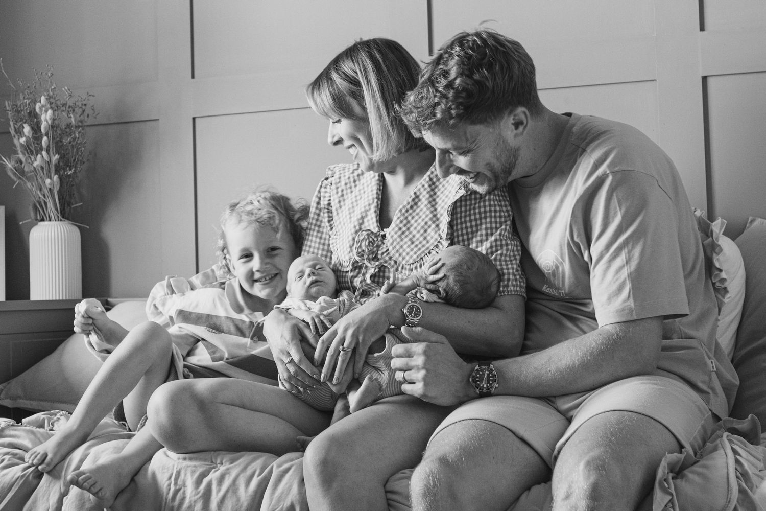 Family relaxing together on grey couch during casual indoor moment.