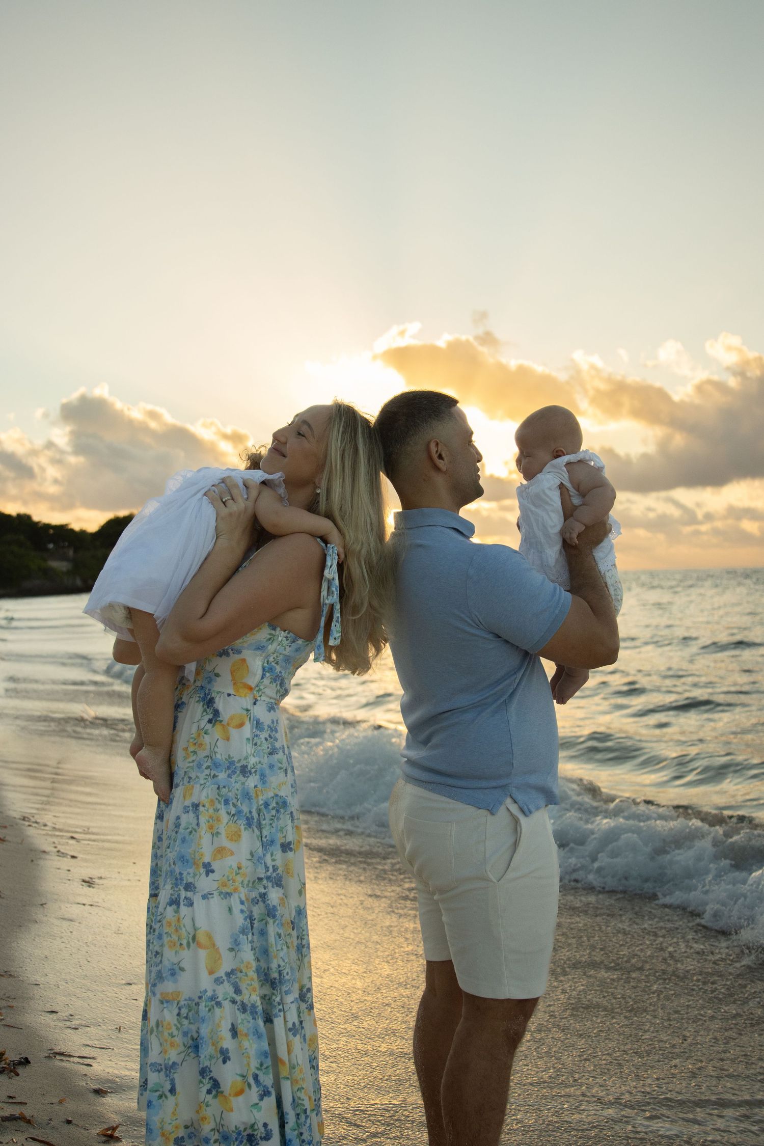 A couple shares a romantic moment at sunset on a tropical beach with waves crashing on the shore.