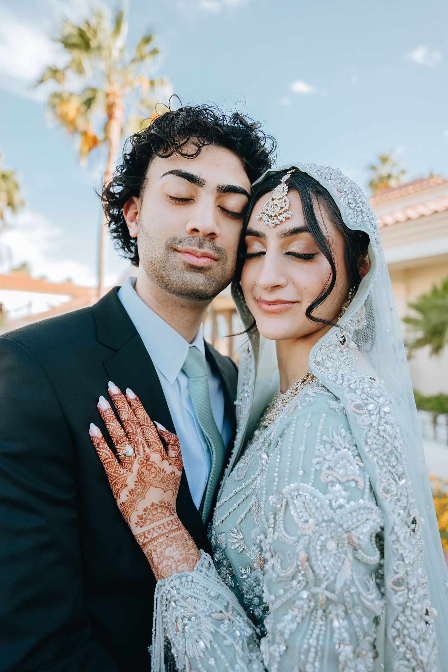A romantic wedding photoshoot outdoors with traditional attire and intricate henna designs.