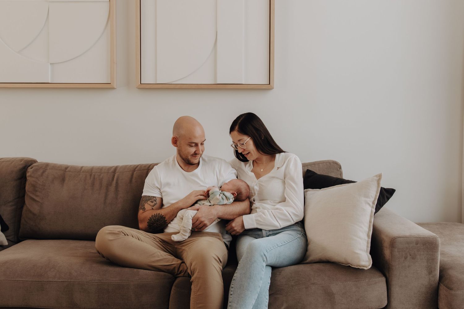 Tender family moment on a brown couch with small baby in a cozy living room setting.
