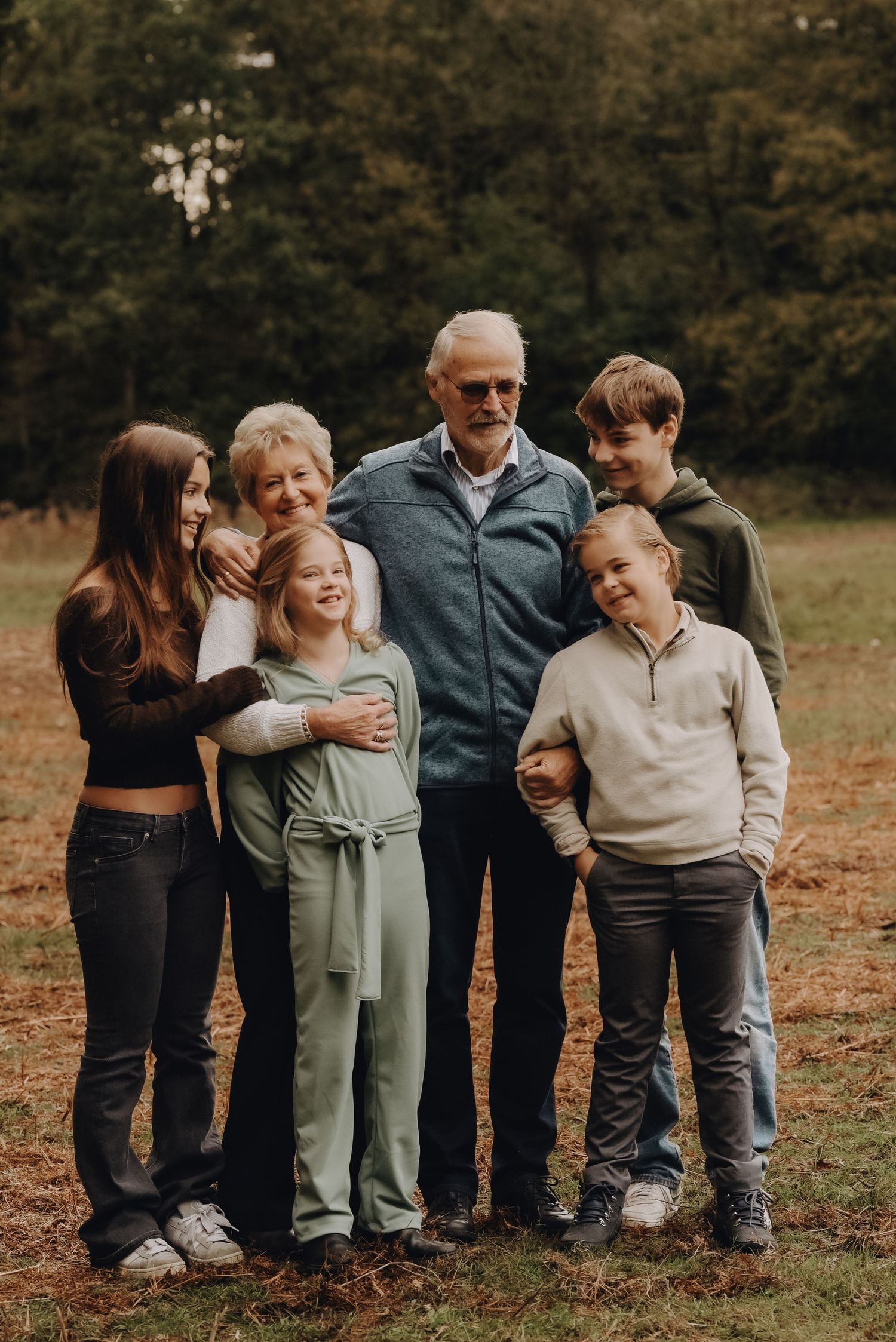 Casual outdoor family portrait of multi-generational group in autumn setting.