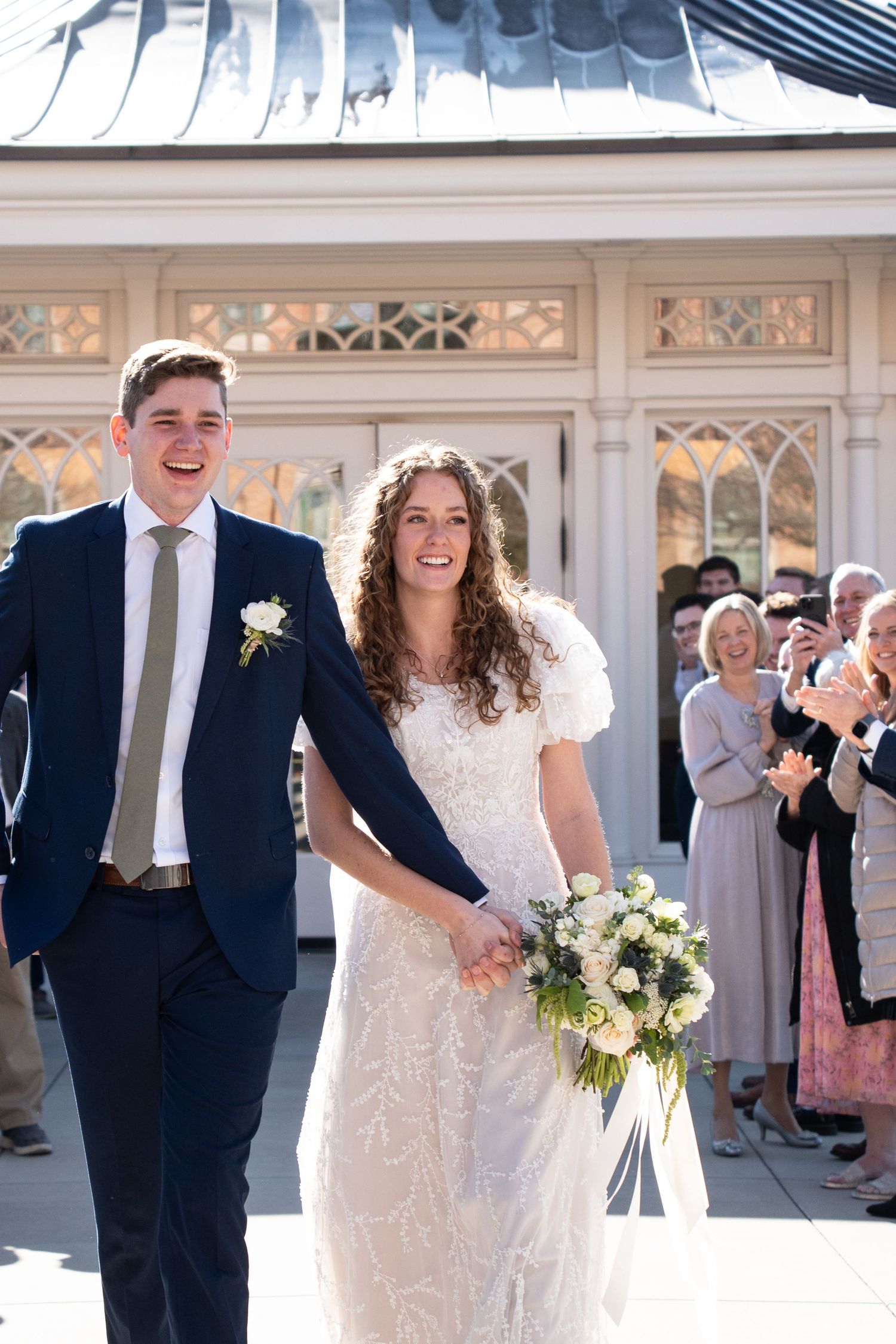 laughing bride and groom exit provo city center temple surrounded by family and friends wedding day ceremony