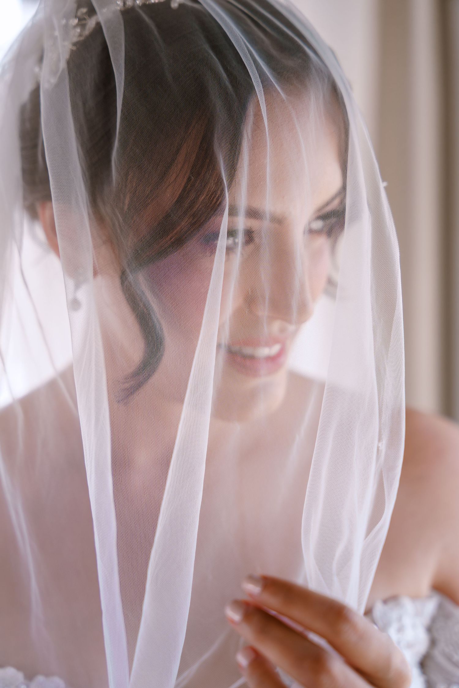Una novia sonríe bajo un velo blanco translúcido en una serie de retratos de boda suaves y románticos.
