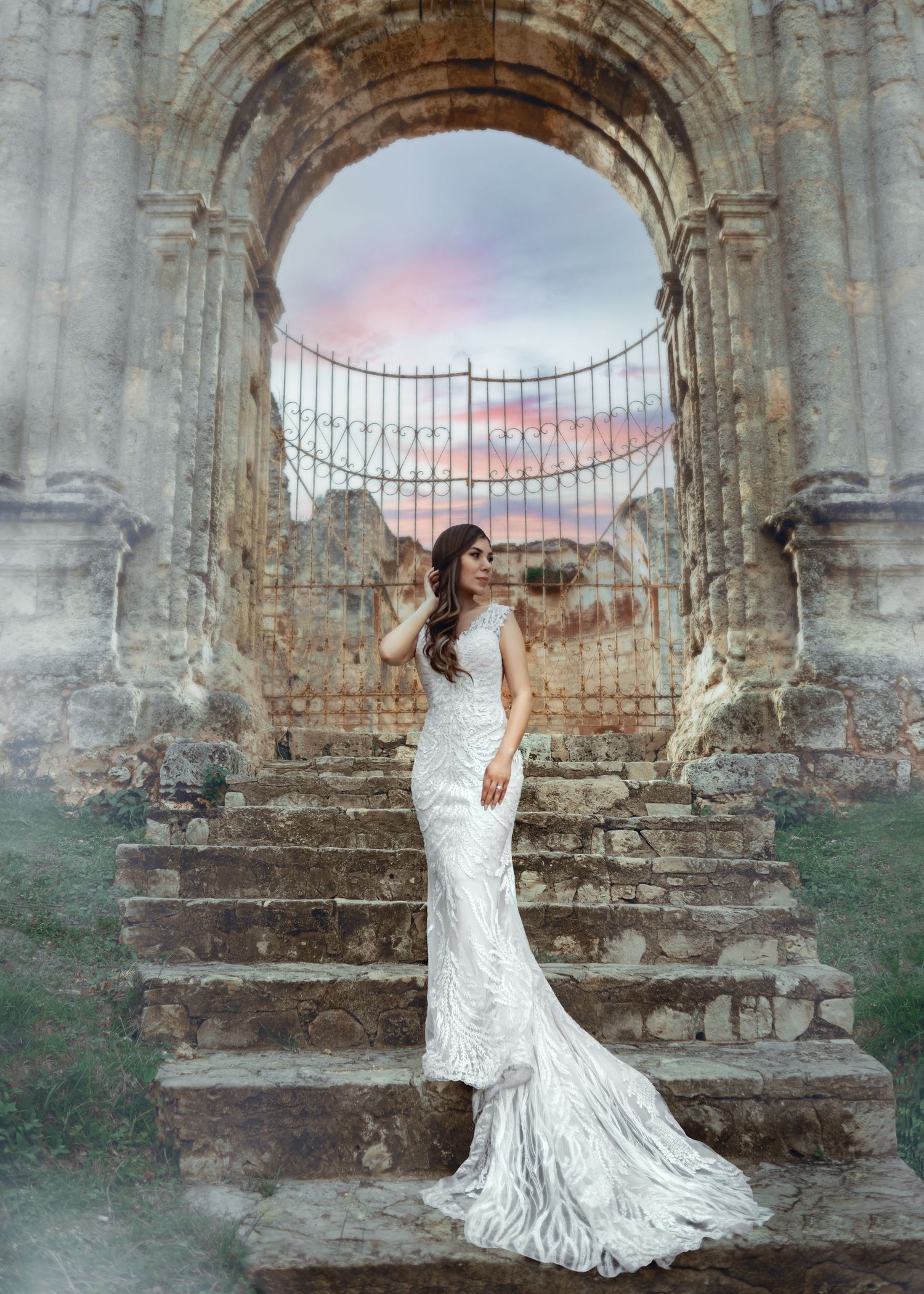 Una novia con un vestido de encaje blanco fluido posa con gracia junto a antiguos arcos de piedra al atardecer.