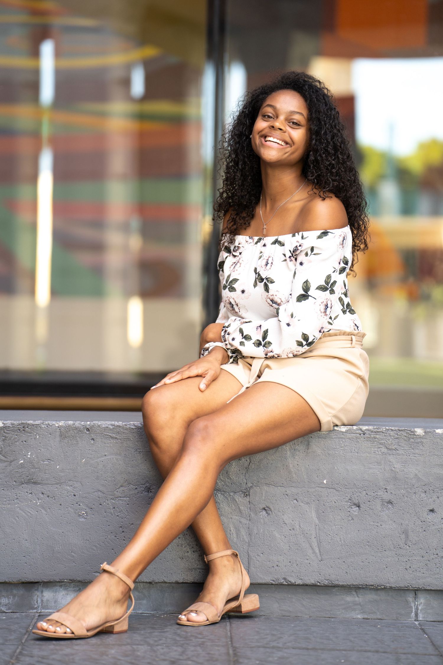 Summer fashion portrait featuring off-shoulder floral top and beige shorts with sandals.