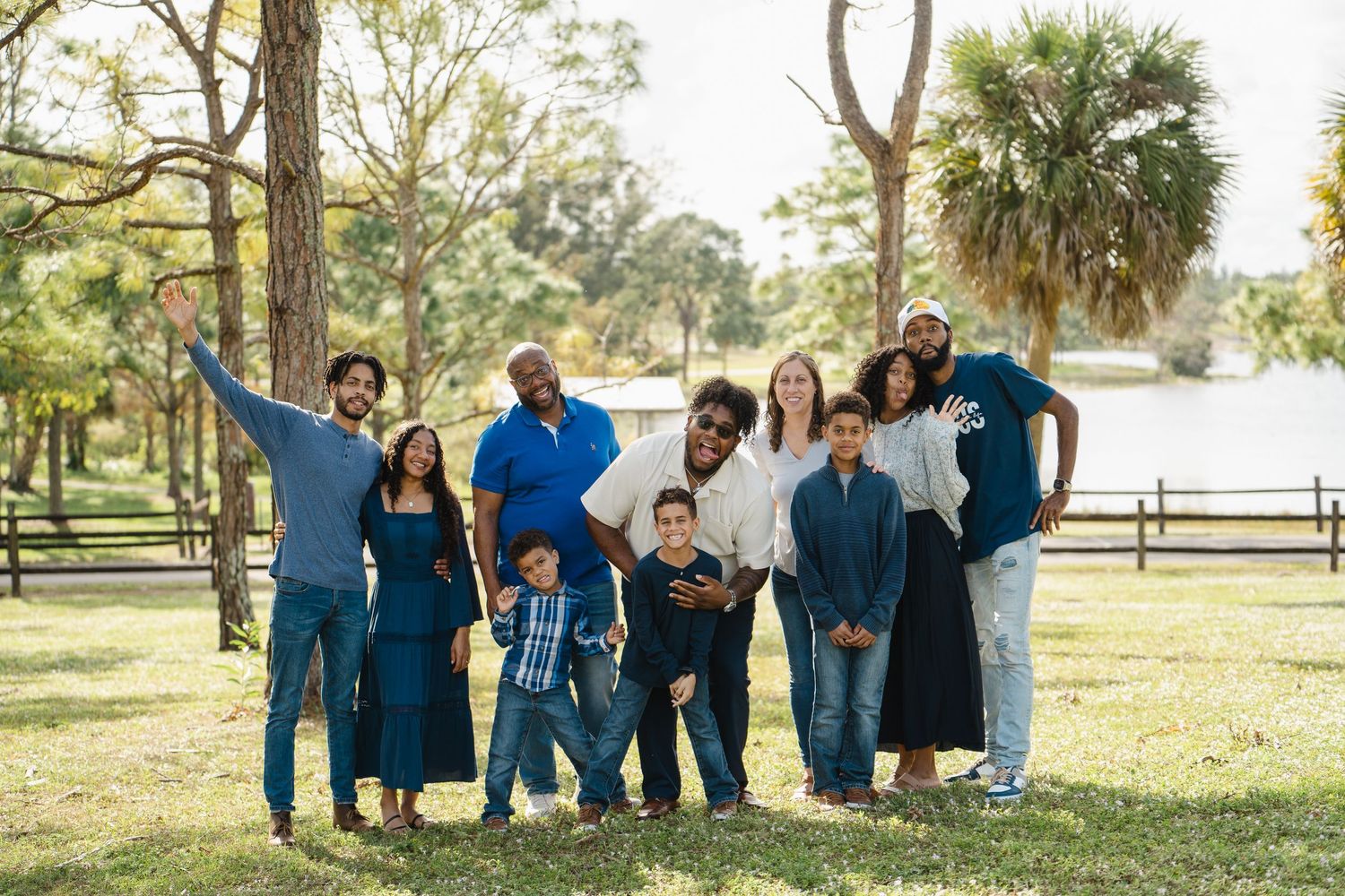 Multi-generational family posing together for a portrait in a scenic park setting with palm trees.
