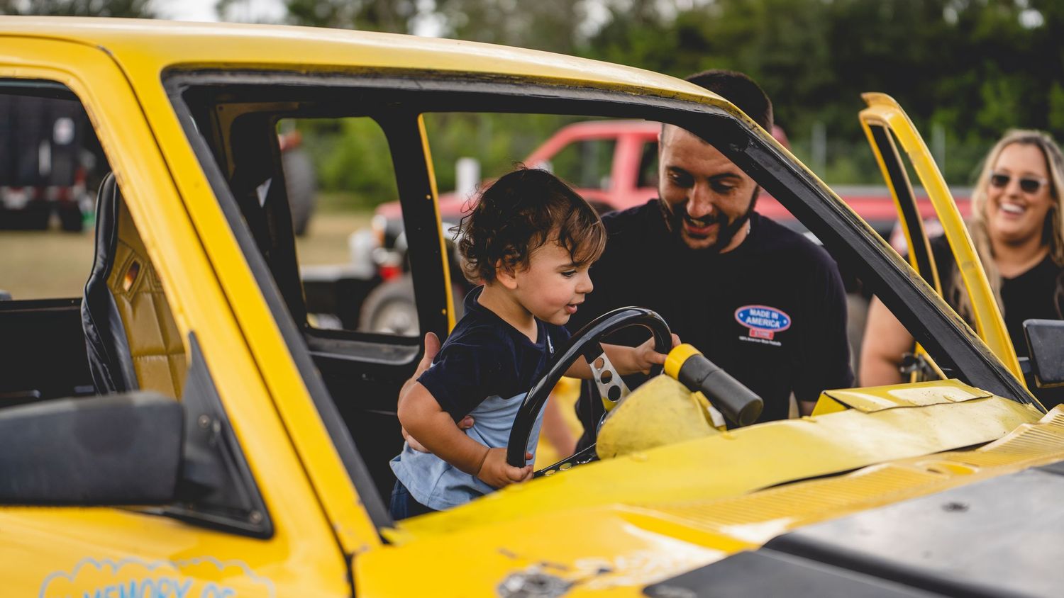 A bright yellow vintage car with people inside sharing a joyful moment.