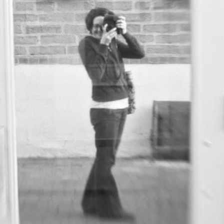 Michelle Rasmussen holding a camera, seen in a reflection