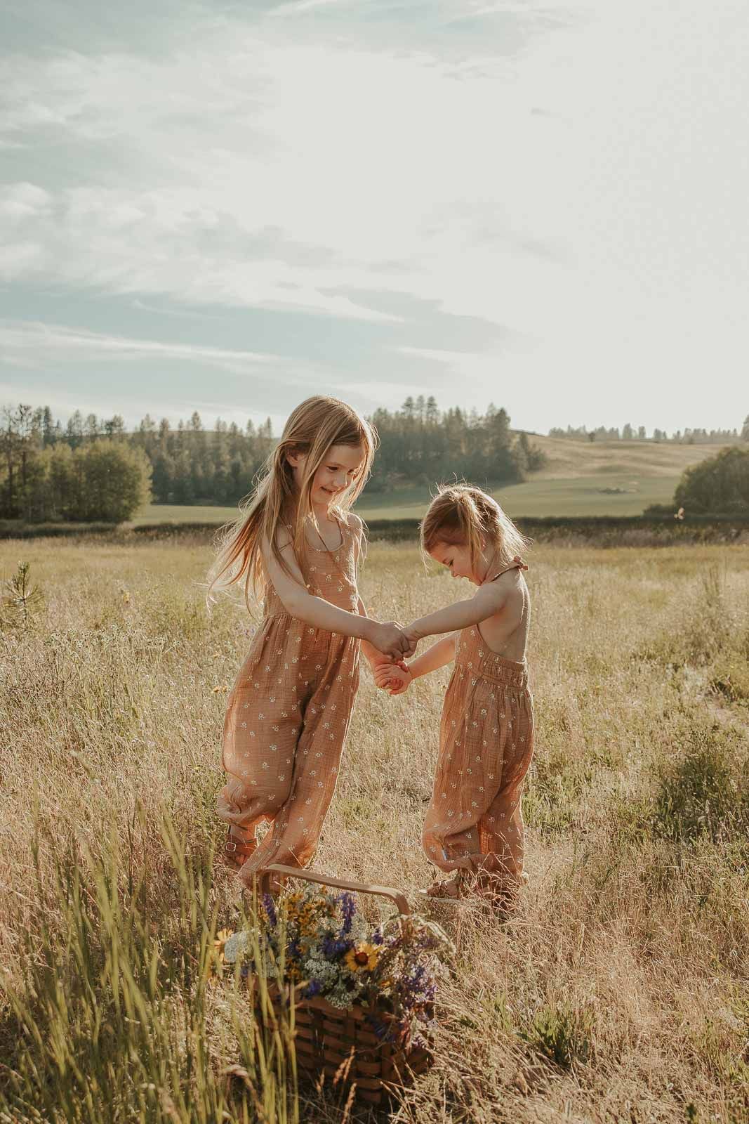 Family of 5 in earth tone outfits at sunset in open field with hills, lake in background at Spokane outdoor photo venue