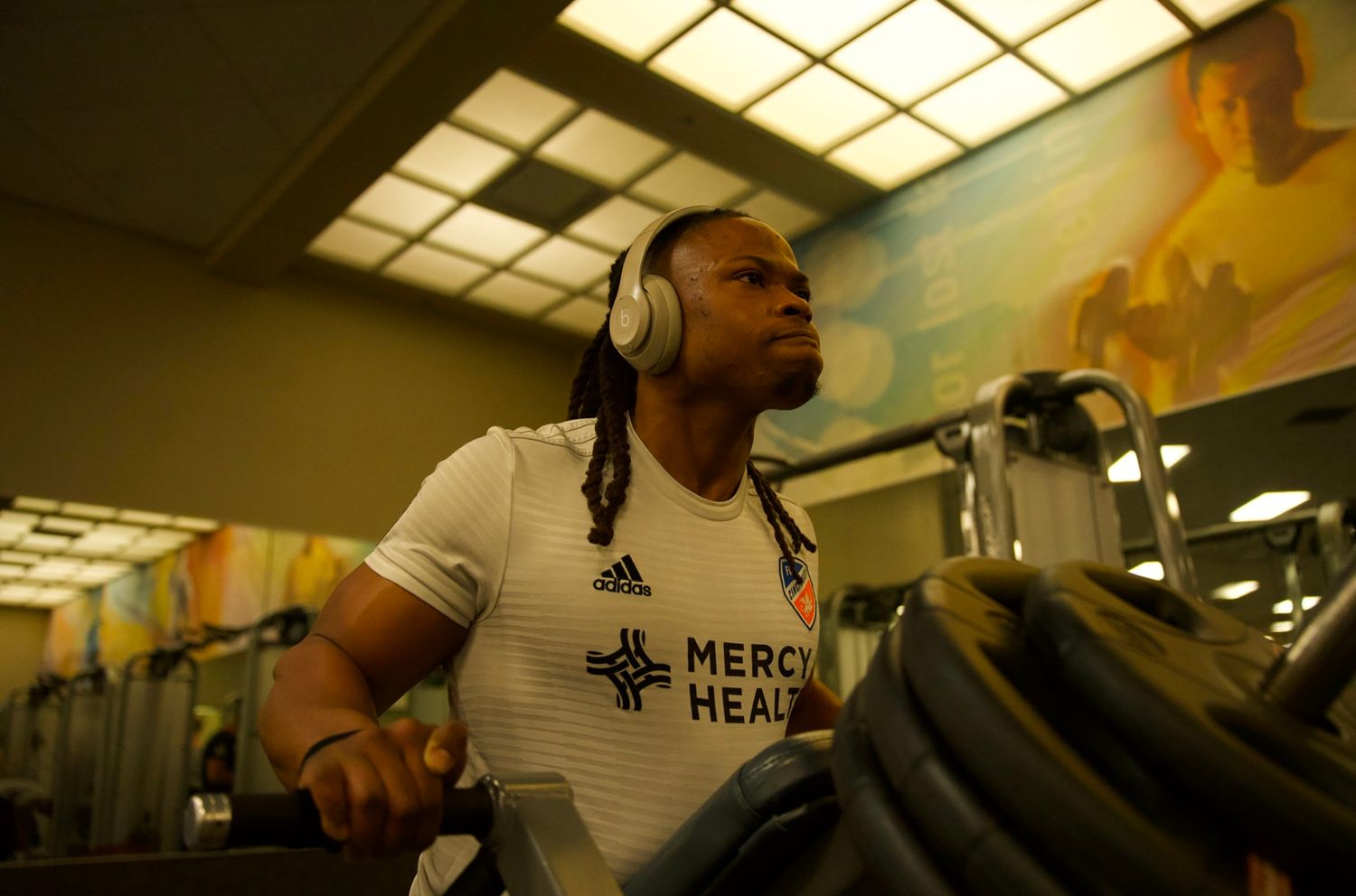 Fitness enthusiasts training with weights in a well-lit indoor gym facility.