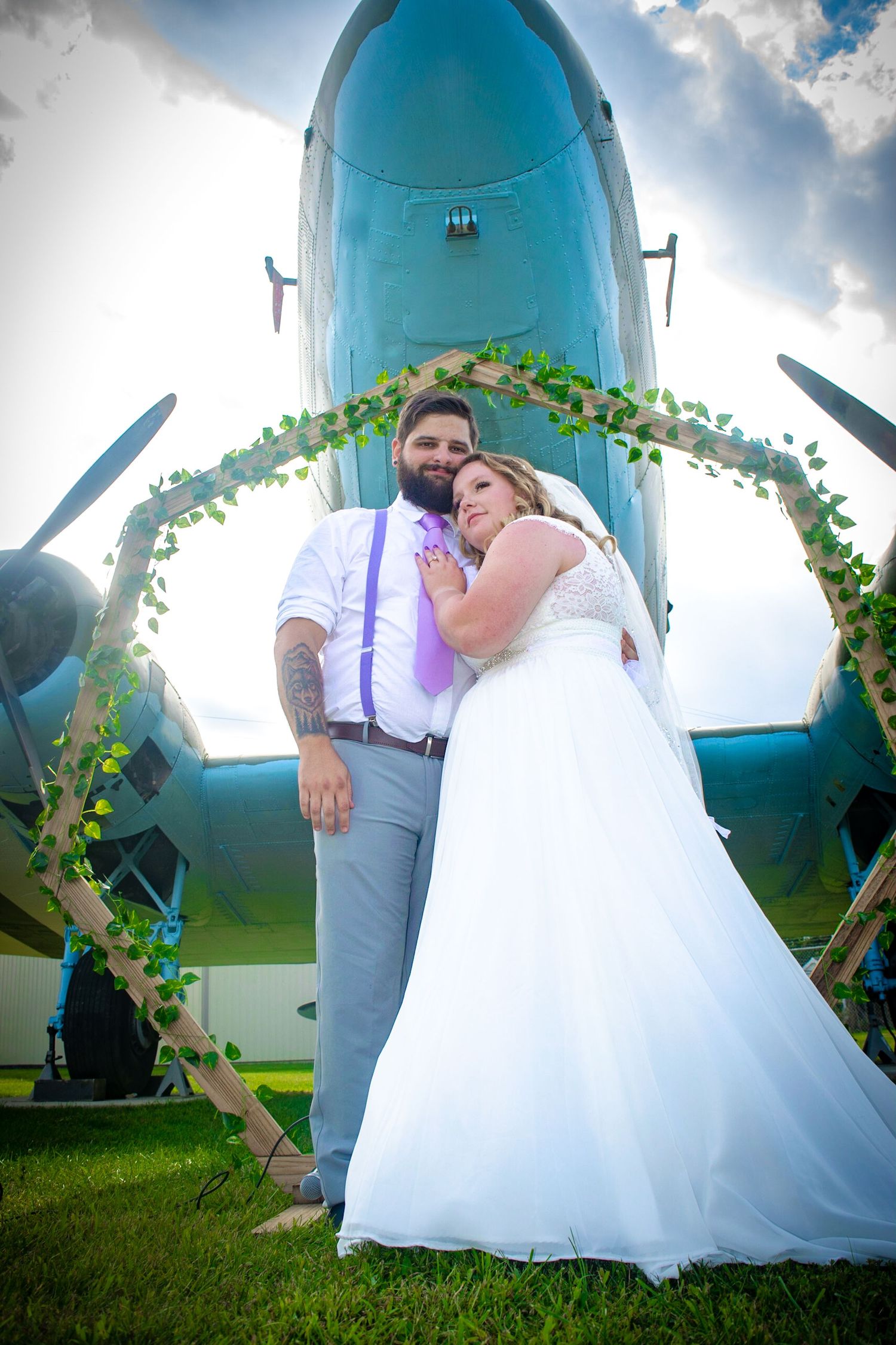 Romantic wedding photos captured against a turquoise vintage airplane with decorative greenery.