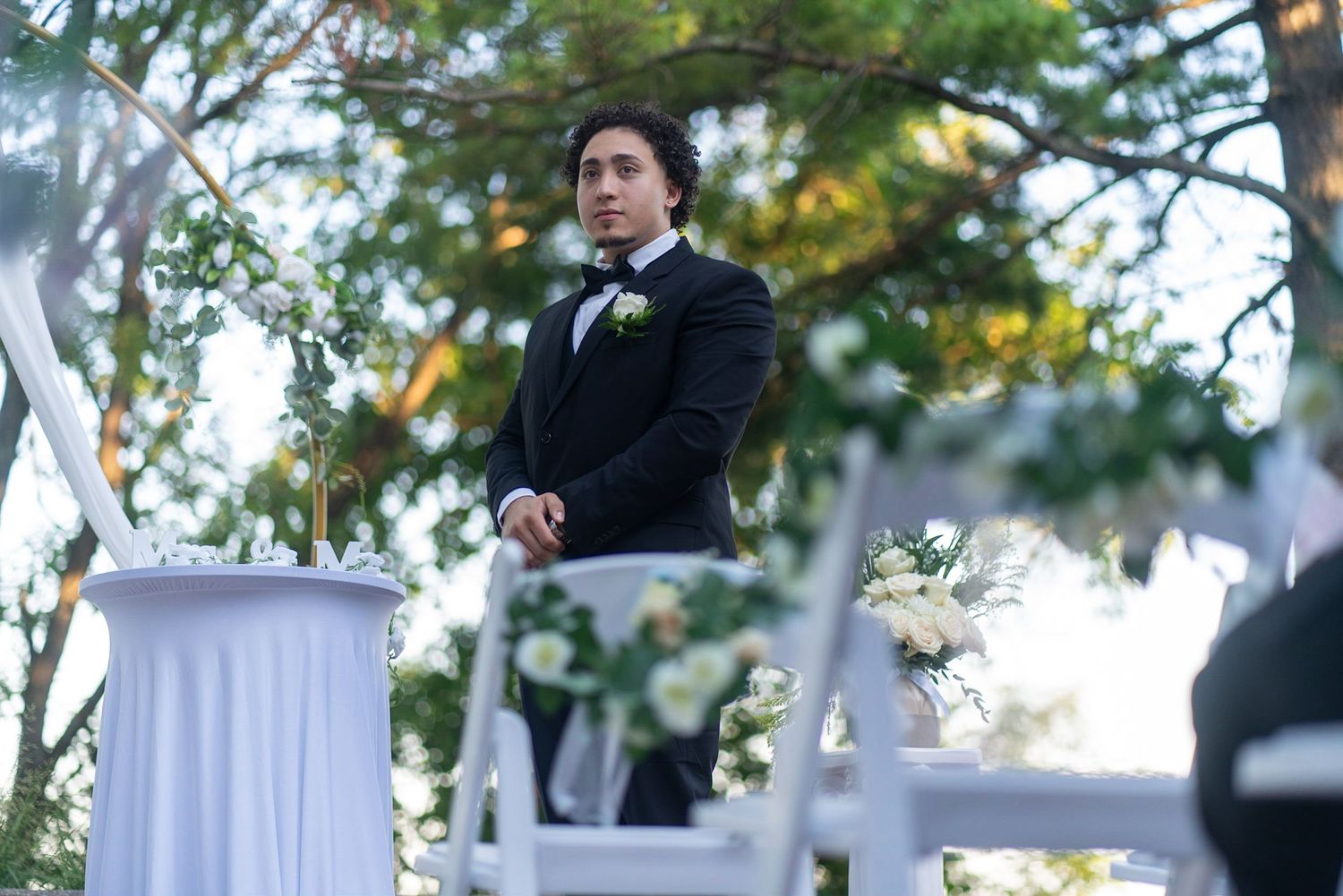 Outdoor wedding ceremony setup with white drapes and floral arrangements.