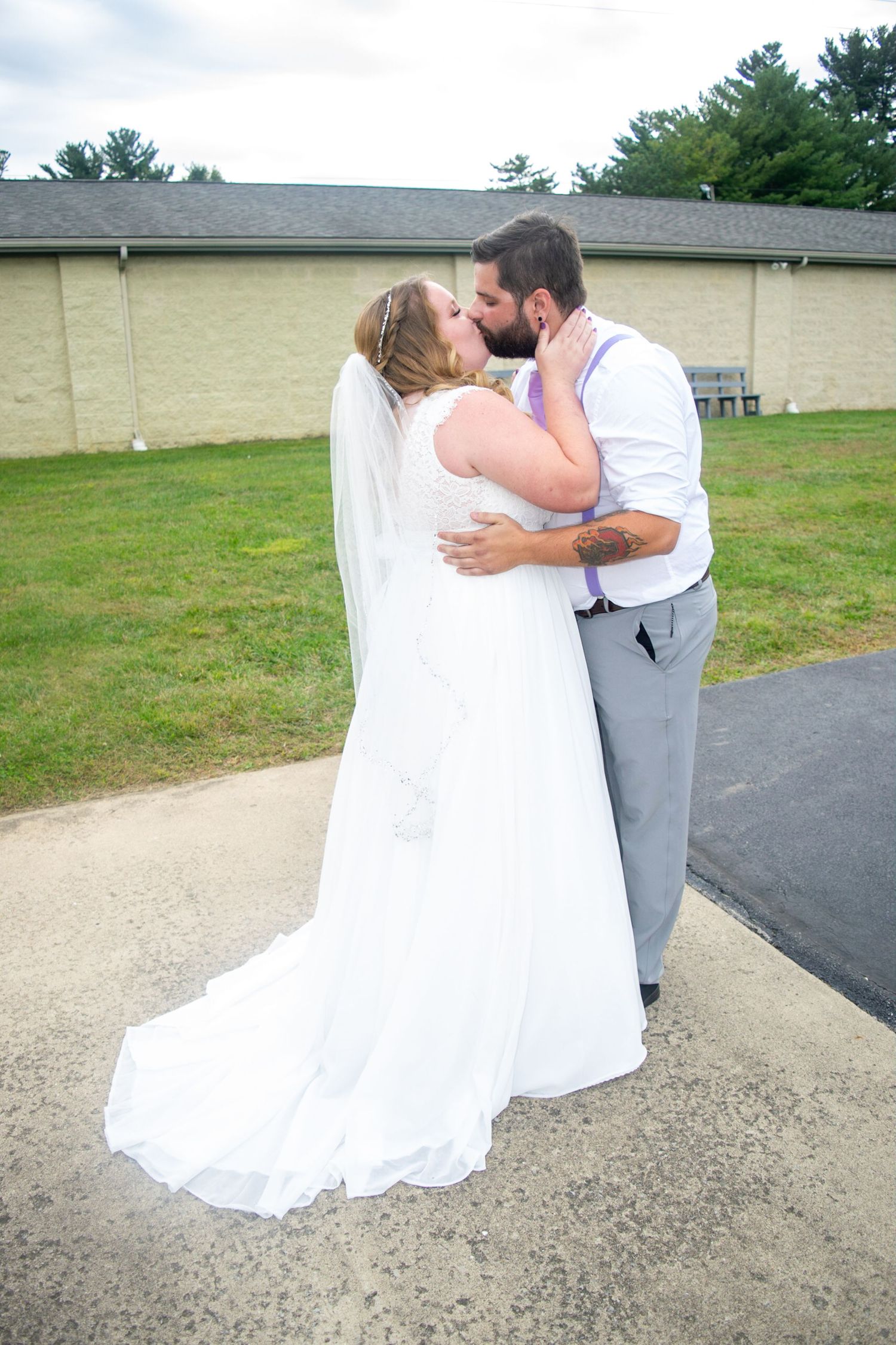 Wedding couple shares intimate moments on a paved pathway outside.