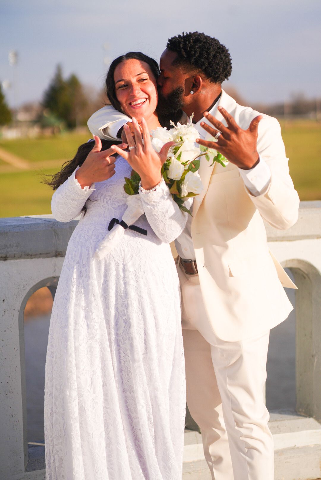 Wedding couple in white sharing joyful laughter during their waterfront photo session.