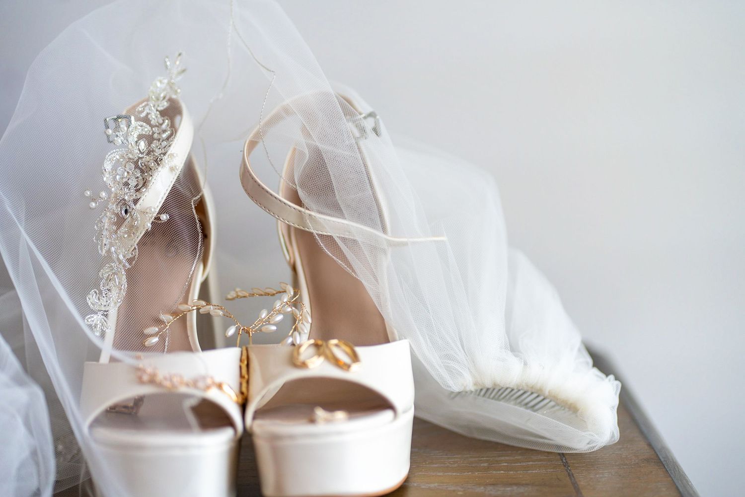 Elegant white bridal shoes and accessories arranged on a light background.
