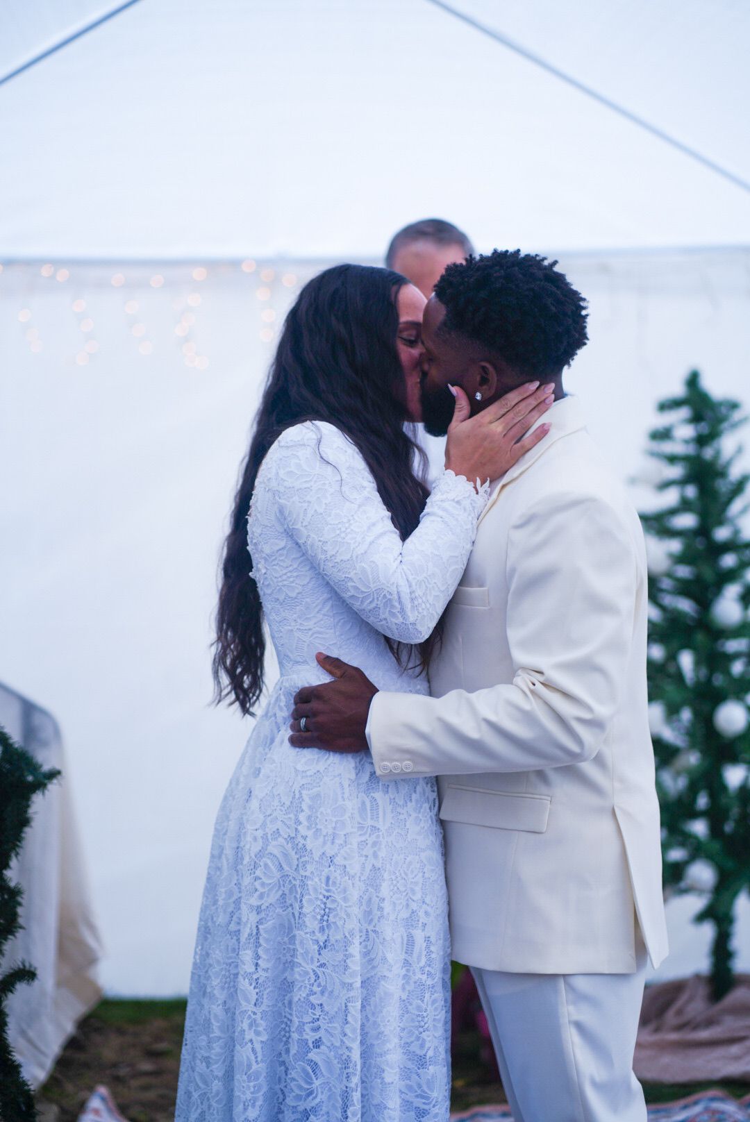 A romantic wedding ceremony moment with a couple in white attire sharing a tender kiss.
