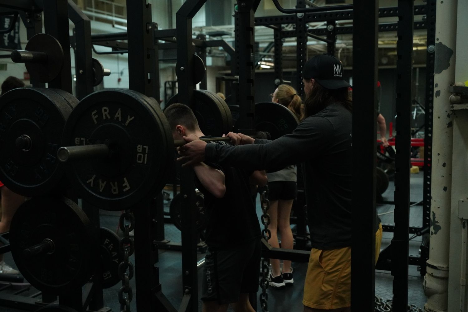 Dark interior shot of weightlifting equipment and training stations in a gym.