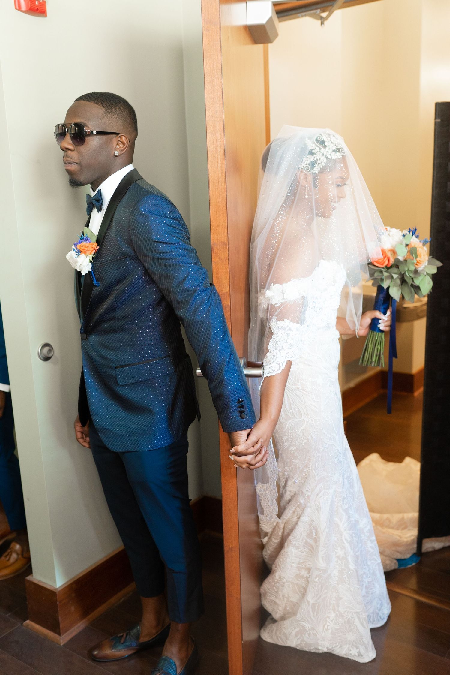 Wedding couple poses in a hallway during their first look photos.