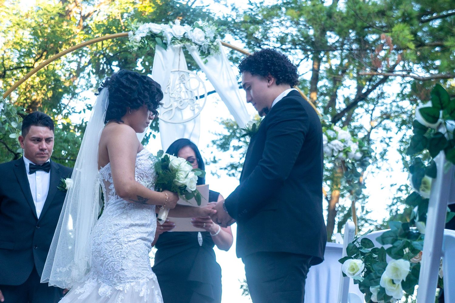 Outdoor wedding ceremony with white decor and floral arrangements.