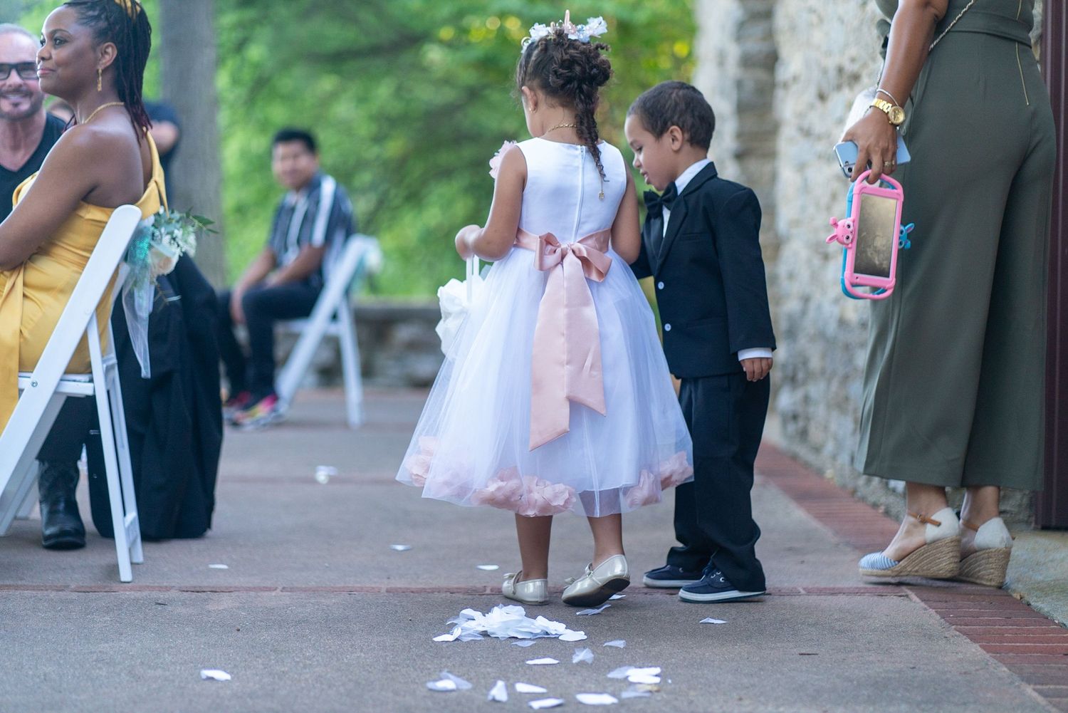 Wedding party members walk along a stone path during an outdoor celebration.