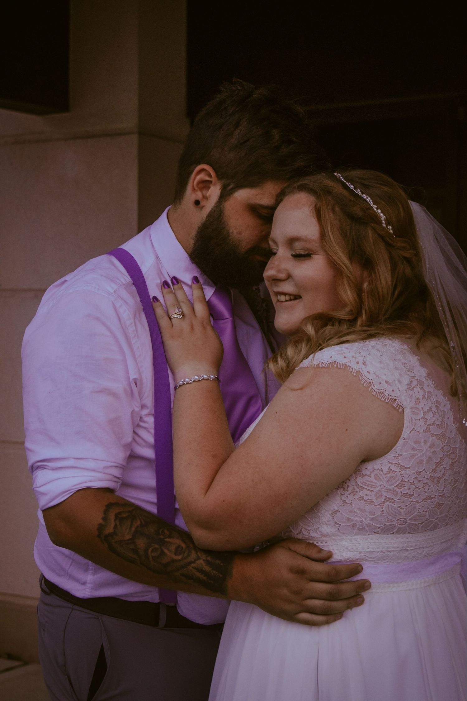 Close-up shots of a romantic embrace between newlyweds in white and purple wedding attire.